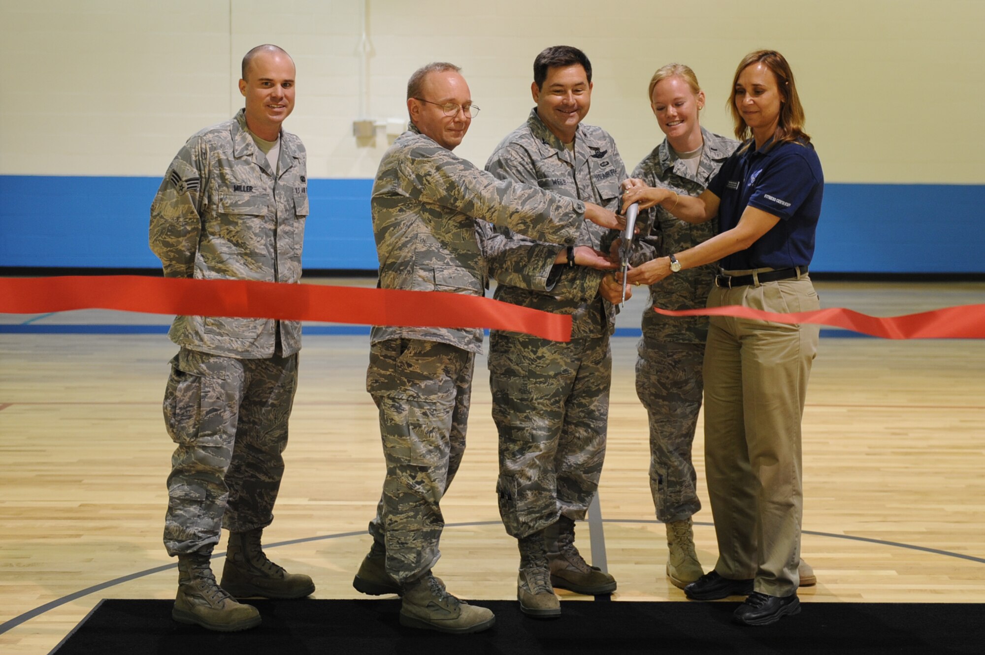 SCOTT AIR FORCE BASE, Ill. -- Senior Airman David Miller, 375th Contracting Squadron, Col. Mark Whinnery, 375th Mission Support Group commander, Col. Kevin Webb, 375th Air Mobility Wing vice commander, 1st Lt. Kristen Fuller, 375th Civil Engineer Squadron, and Gailyn Gonzalez, 375th Force Support Squadron, all of whom were key players in the success of getting a new floor for the James Gym, cut the ribbon that officially opened the basketball courts Sept. 1. In addition to the new floor, the gym also has new bleachers and was repainted. (U.S. Air Force photo/Senior Airman Tristin English)