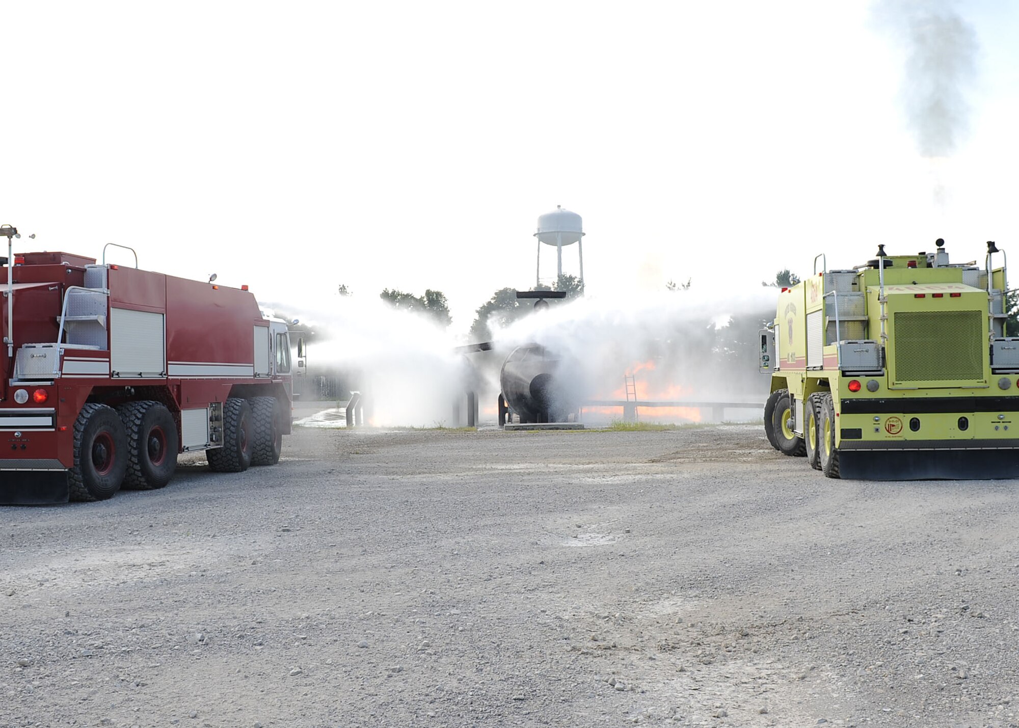 SCOTT AIR FORCE BASE, Ill. -- Two fire teams from the 375th Civil Engineer Squadron Fire Department work together to extinguish flames surrounding a training jet Aug. 12 during a Live Fire Certification test. In addition to realism, exercises like these help firefighters become comfortable and confident with their personal protective equipment. (U.S. Air Force photo/Senior Airman Samantha S. Crane)