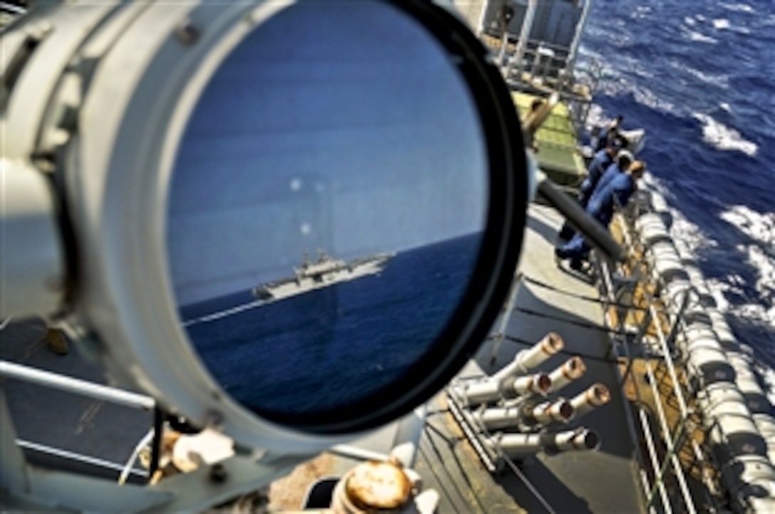 Reflected in a signal lamp, the amphibious assault ship USS Kearsarge passes the amphibious transport dock ship USS Ponce as the Ponce sailors watch the exercise called a "leap frog" at sea, Sept. 6, 2010. The Ponce is part of the Kearsarge Amphibious Readiness Group, which is delivering food, water and equipment to support the humanitarian relief efforts for Pakistani flood victims. 