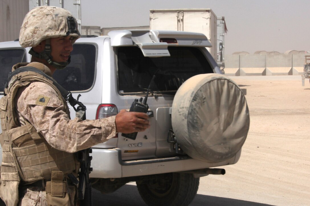 Sgt. Oliver Ventura, a Base Defense Augmentation Force Marine with 3rd Low Altitude Air Defense Battalion, waves vehicles to the inspection site at one of the main entry points here. Ventura, an armory technician from Marine Corps Air Station Miramar, Calif., and 32 other Marines, volunteered to support 3rd Marine Aircraft Wing (Forward)’s requirement to augment the base defense force. The Marines are serving a three-month deployment manning towers, gates and main entry points for eight hours each day.