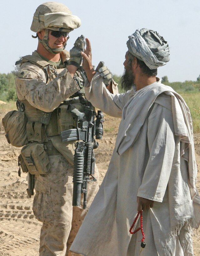Sgt. Cody T. Romriell, a combat engineer with 2nd Battalion, 9th Marines, high-fives a local after helping him unclog a backed-up canal during the construction of Typhoon 3 in Marja, Afghanistan, Sep, 9. Marine engineers with 2/9 have been constructing new patrol bases in their area of operation in order to increase force protection. Typhoon 3 is one of the many being built.