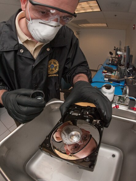 Scott Lalliss uses a magnifying lens to check a hard drive that is being cleaned in a sonic cleaner with 91 percent alcohol solution at the Defense Computer Forensic Laboratory Sept. 9, 2010, in Linthicum, Md. The 9 percent of water in the solution develop bubbles that gently move dirt and other organic matter away from the disks that may contain valuable evidence in an investigation. Mr. Lalliss is a senior forensic technician. (U.S. Air Force photo/Lance Cheung)