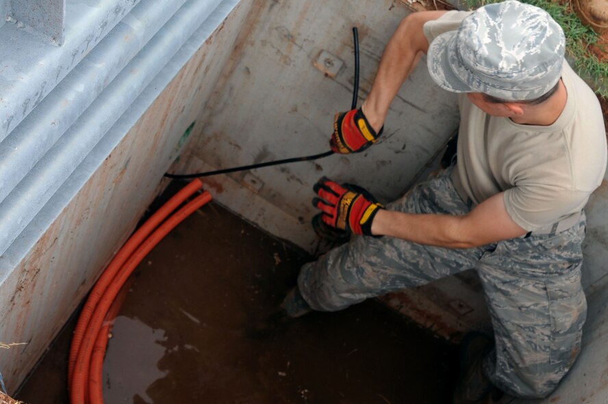 BARKSDALE AIR FORCE BASE, La. -- Airman 1st Class David Montroy, 2nd Communications Squadron antenna systems apprentice pulls a 12 pair cable through the first hand hole into the manhole so they can be spliced into a 1200 pair cable Sept. 9. The 12 pair feeds a High Frequency hut on the east side of the flight line for radio maintenance. (U.S. Air Force photo by Senior Airman Brittany Y. Bateman)(RELEASED) 
