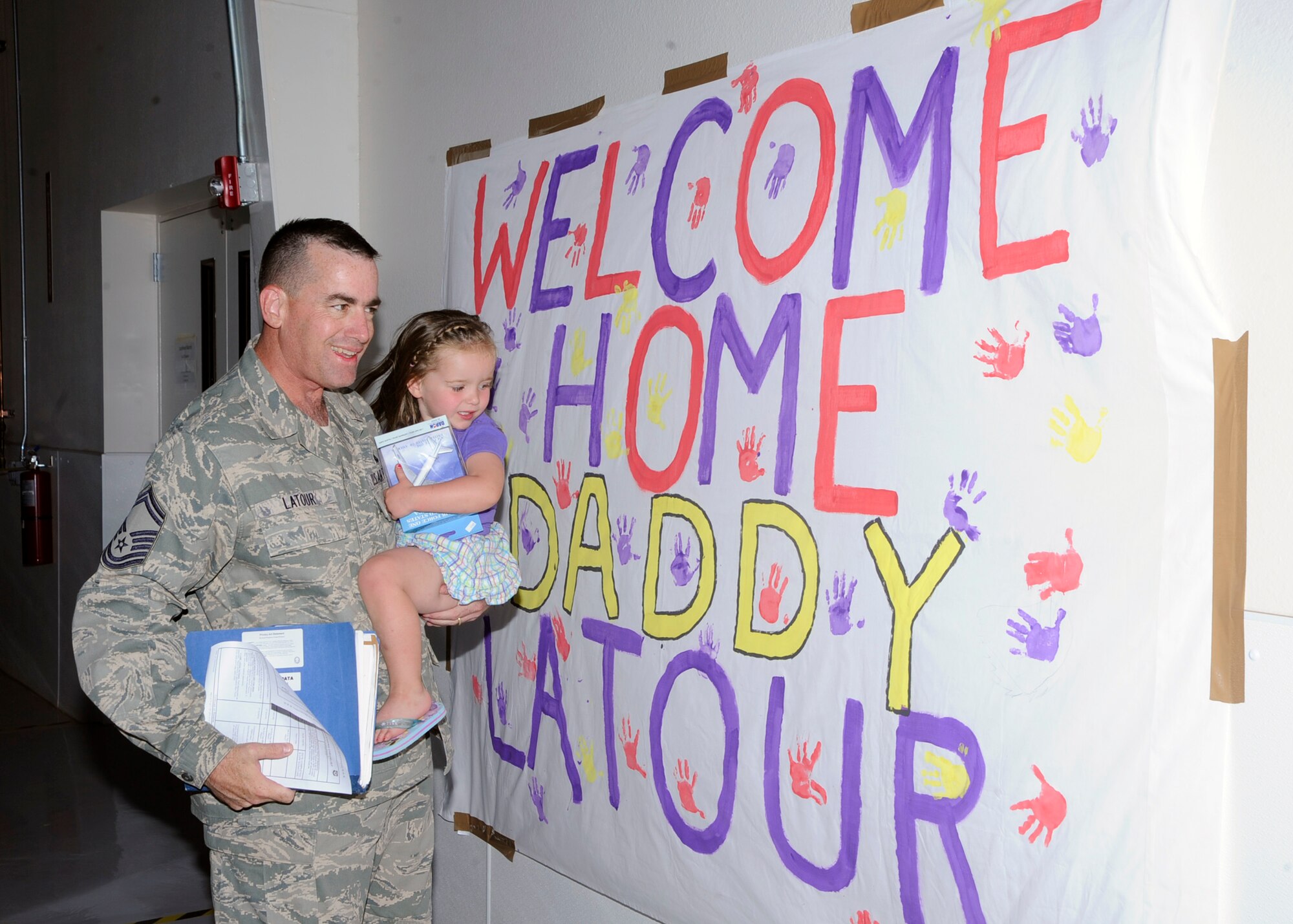 Senior Master Sgt. Thad LaTour and his 2 1/2-year old daughter Addison, look at the welcome home sign made for him Sept. 4, following his return from deployment. Thirty-three Airmen returned to Cannon Air Force Base, N.M., following their tour of duty in Southwest Asia. (U.S. Air Force photo by Greg Allen) (Released) 