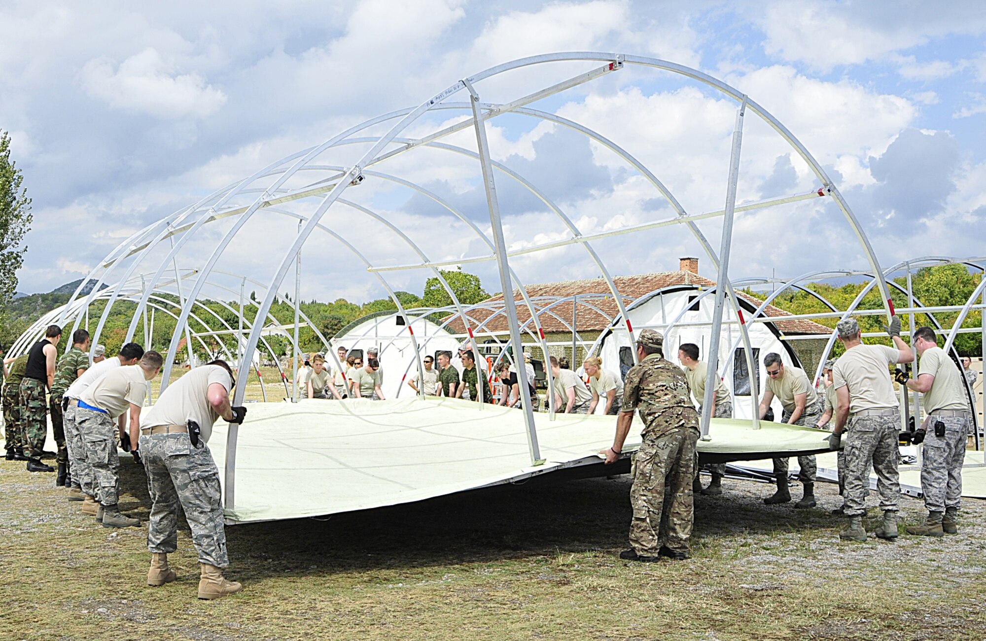 Armed Forces members from different nations work together to move a medical tent frame at Danilovgrad Army Base, Montenegro, Sept. 9. The medical tents will be used during MEDCEUR 10, a medical training exercise for central and eastern Europe. For more information visit www.usafe.af.mil/medceur.asp and www.odbrana.gov.me. (U.S. Air Force photo/Airman 1st Class Tiffany Deuel)