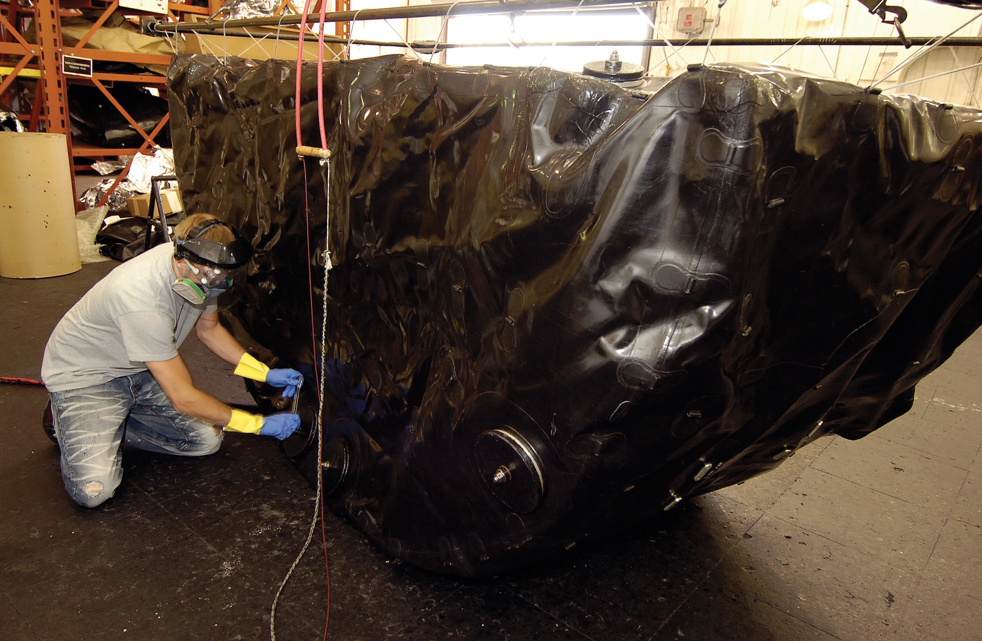 David Hutchison works on a KC-135 fuel bladder, one of 16 from the body of the aircraft. To check for leaks in the rubber, ammonia is put in the bladder and it is pressurized. A specially treated cloth is put over the pressurized bladder and any leaks will show pink on the cloth. (Air Force photo by Margo Wright)