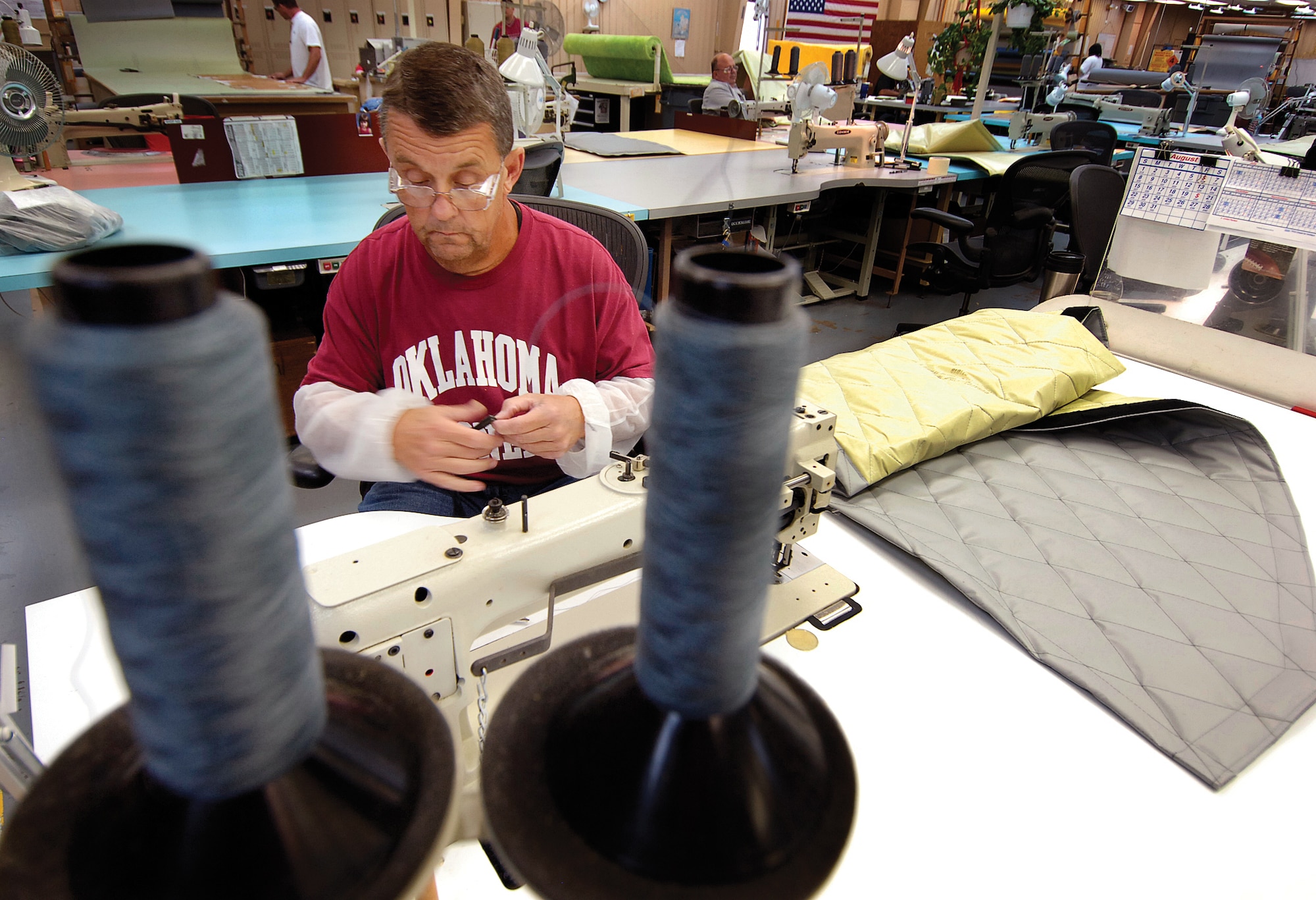 Glenn Breshears sews electrical control panel covers for KC-135s.  Each -135 has two such covers and the shop is doing the work for the entire fleet as a one-time special project. Mr. Breshears wears protective sleeves on his arms to keep the panels’ scratchy fibers away from his skin. (Air Force photo by Margo Wright)