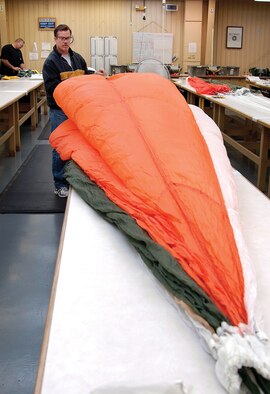 David Weiss packs a 28-foot long B-1B spare personnel parachute.  Chutes are inspected and repacked every four months in the Fabric and Life Support Unit. “We hope what we do is the biggest waste of time,” says unit chief Ann Jones. “Our goal is for our gear to never be used. But if they need it, it’s done right.” (Air Force photo by Margo Wright)