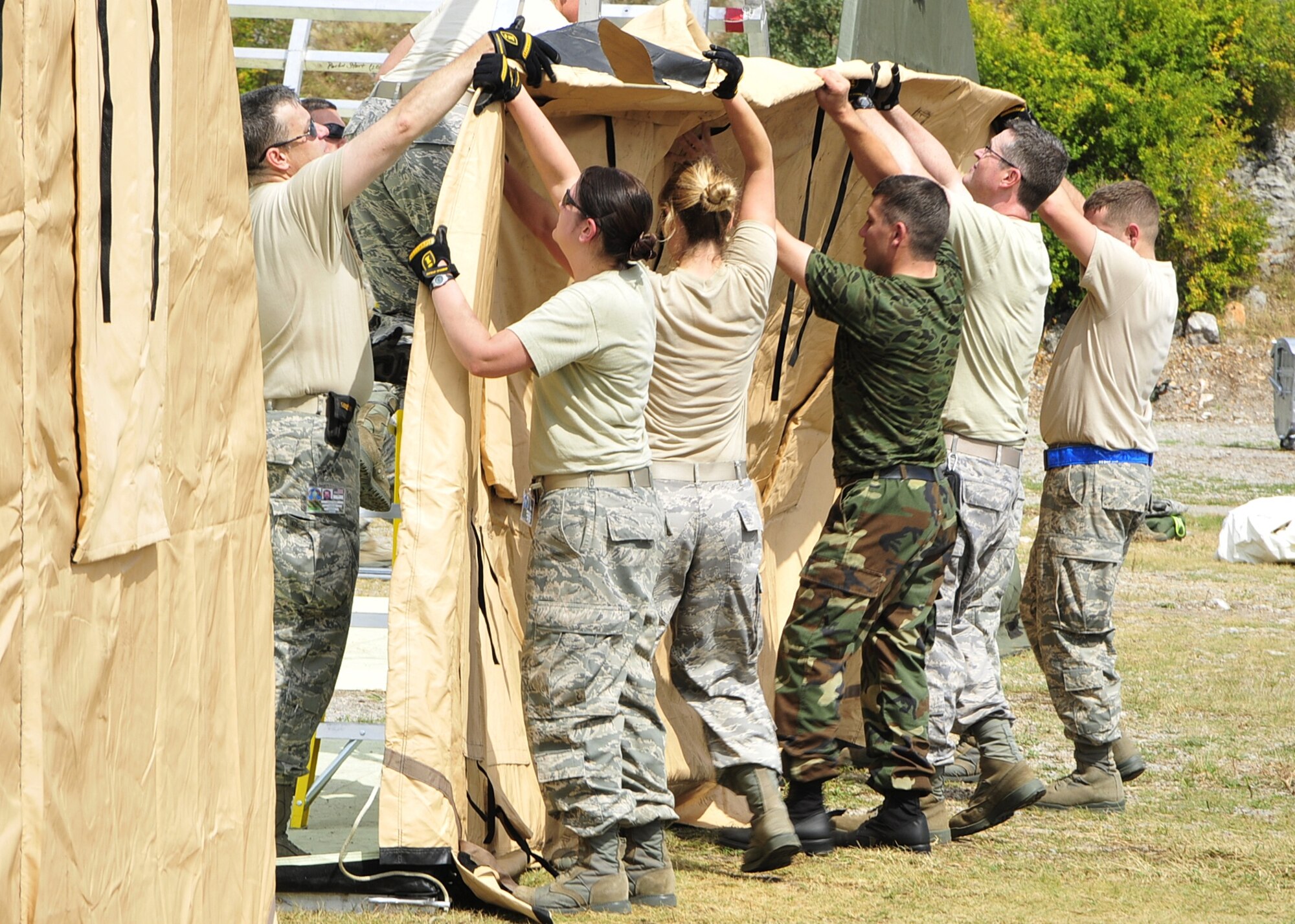 United States Airmen and an Azerbaijani soldier cover a tent frame with a tarp at Danilovgrad Army Base, Montenegro, Sept. 9. The medical tent will be used during MEDCEUR 2010, a medical training exercise for central and eastern Europe, in which 10 nations will participate. For more information visit www.usafe.af.mil/medceur.asp and www.odbrana.gov.me. (U.S. Air Force photo/Airman 1st Class Tiffany Deuel)