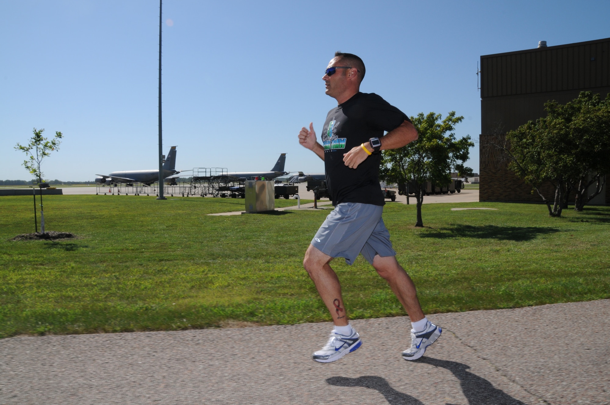 Master Sergeant Marty Hogan runs along the flight line at the Sioux City, Iowa Air National Guard Base.  Hogan, a staff accountant at the 185th Air Refueling Wing, wears a pink ribbon tattoo on his leg in honor of his wife's battle with cancer.
USAF Photo: Master Sgt Vincent De Groot 185th ARW Public Affairs Manager

