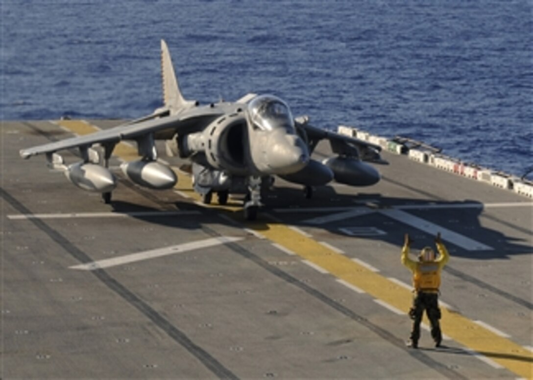 U.S. Navy Petty Officer 1st Class Michael Quintos directs an AV-8B Harrier jet aircraft as it taxies on the flight deck of the forward-deployed amphibious assault ship USS Essex (LHD 2) while underway in the Sea of Japan during the fly-on of the 31st Marine Expeditionary Unit’s aviation combat element on Sept. 5, 2010.  