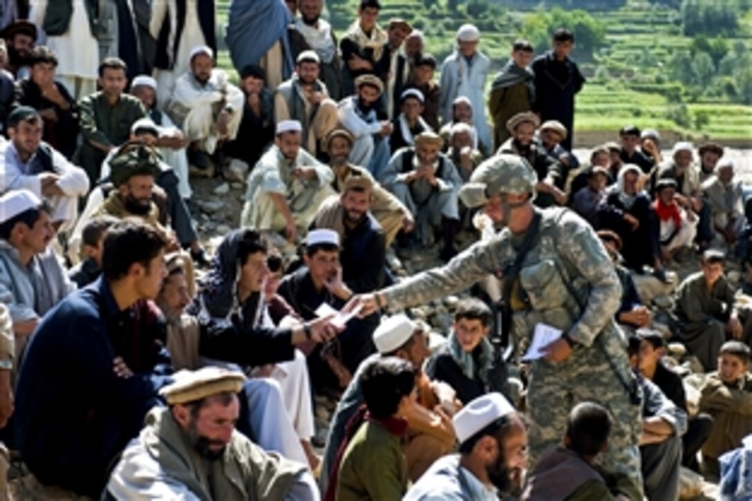 U.S. Army Spc. Joshua McDaniel passes out flyers wishing Joybar residents a happy Ramadan in Afghanistan's Kapisa province, Sept. 9, 2010. McDaniel is assigned to the Provincial Reconstruction Team Kapisa. A crowd from nearby villages gathered to watch a shura between village elders and the team discuss concerns about road construction near their farmland.