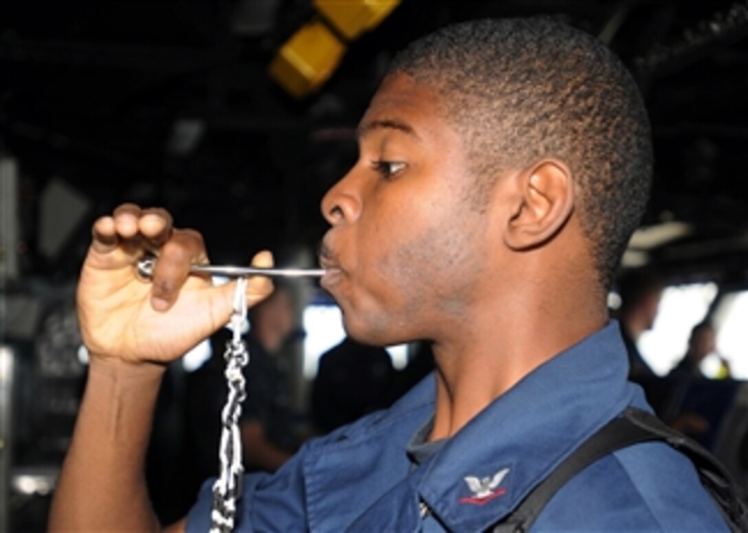 U.S. Navy Boatswain's Mate 3rd Class Aaron Shorts pipes the mess call into the main public address circuit aboard the amphibious assault ship USS Peleliu (LHA 5) underway in the north Arabian Sea in support of disaster relief operations in Pakistan on Sept. 4, 2010.  