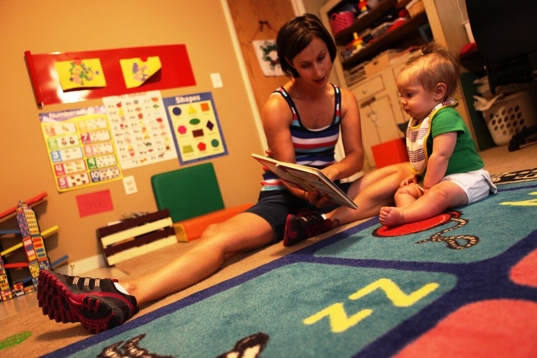 Kristi Battavio, a family child care provider, reads to Kinley Nygaard, a 7-month-old, during the day. Battavio is one of many military spouses who run a child care business in her home through the Family Child Care Program with the Children, Youth and Teens Program, Marine and Family Services Division, Marine Corps Community Services, Marine Corps Base Camp Lejeune.