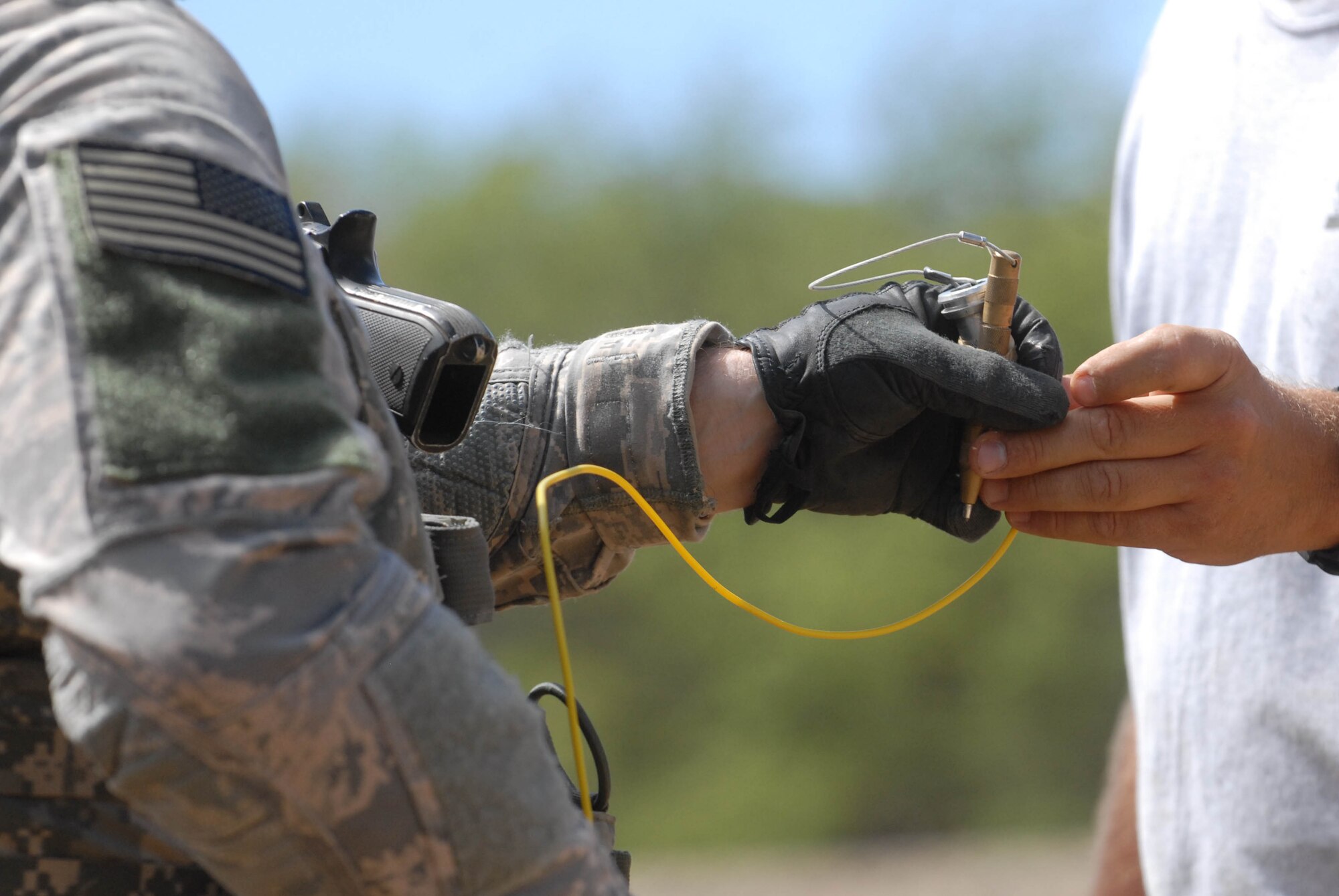 An Army Explosive Ordnance Disposal technician accepts a non-electric firing system from his instructor, the Director of Training for Tactical Energetic Entry Systems and a 20-year Army Special Forces veteran, during a joint-service training event at Joint Base Pearl Harbor-Hickam Sept. 1, 2010. Airmen hosted the 40-hour training event, which focused on breaching and entering techniques. (U.S. Air Force photo/Staff Sgt. Carolyn Viss)