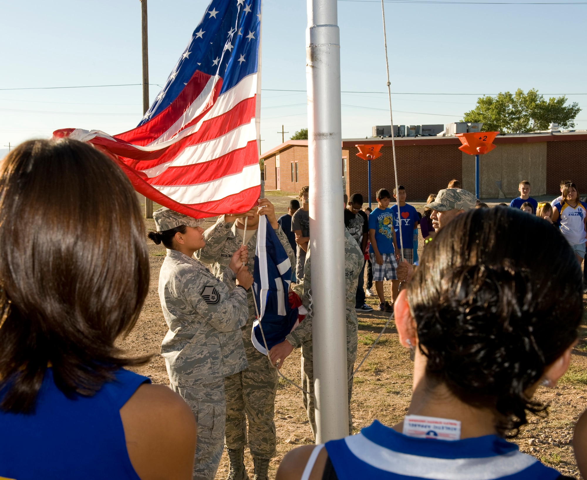 HOLLOMAN AIR FORCE, N.M. -- Students from Holloman Middle School watch members of the 49th Communication Squadron attach the Freedom Flag, Sept. 10, 2010, which was raised in remembrance of the terrorist attacks Sept. 11, 2001. The Freedom Flag was created when a restaurant owner in Virginia, Richard Melito, decided to sketch out a symbol that he felt paid tribute to and honored everyone who lost and risked their lives. Twelve months later, he created a non-profit organization called the Freedom Flag Foundation. The Freedom Flag features two broad red stripes, symbolizing the Twin Towers and the sacrifices of those at the World Trade Center during the attacks, three white stripes in memory of the rescue workers, firefighters, police officers and others who responded to the attacks; and two smaller red stripes to honor the crew and passengers who lost their lives aboard the hijacked aircrafts that day, nine years ago.  (U.S. Air Force photographer Tech. Sgt. Alan Port)