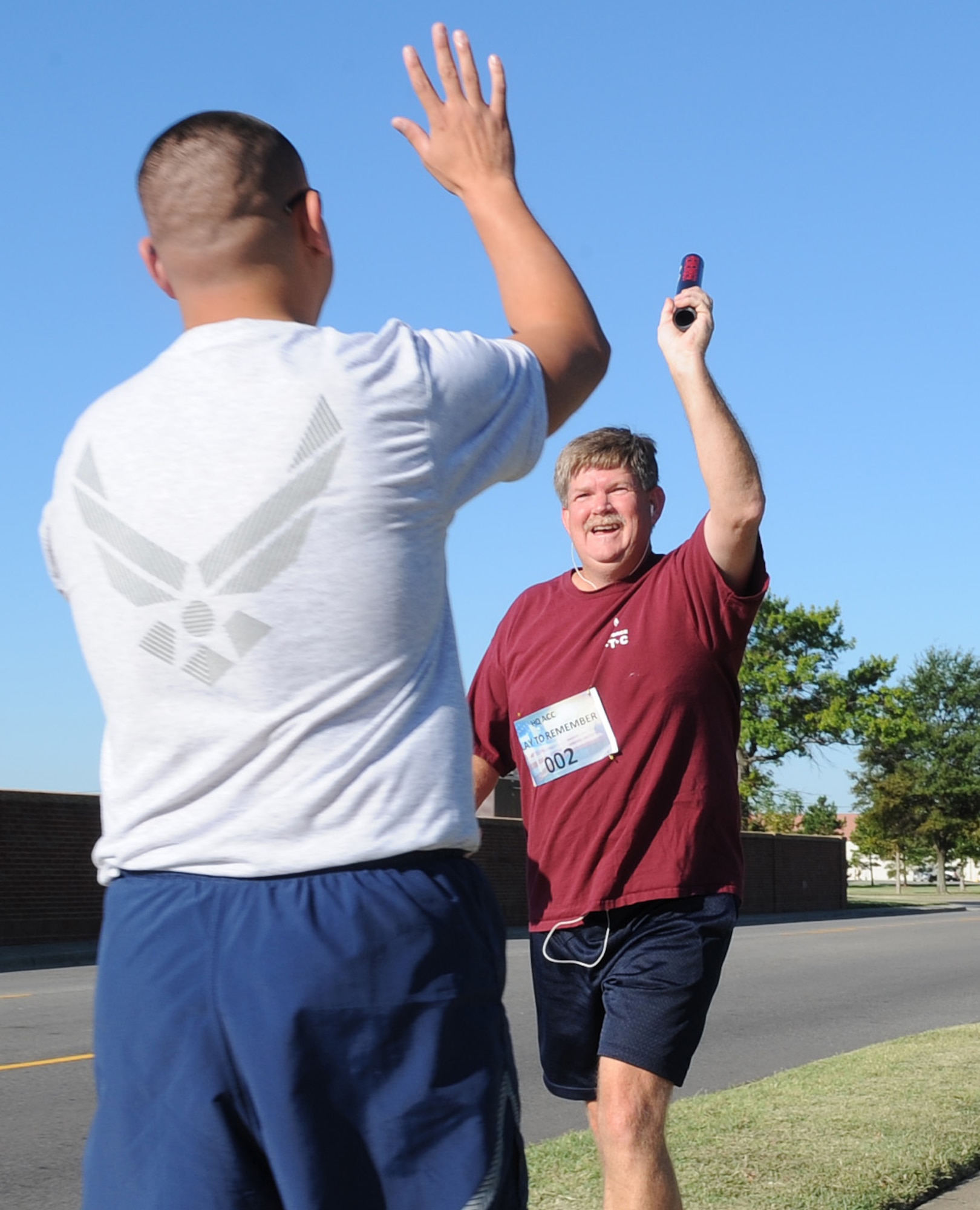 LANGLEY AIR FORCE BASE, Va – Headquarters ACC teammates, Tom Holloway and Tech. Sgt. Chris Fabela, exchange a baton during the 9/11 memorial run Sept. 10, 2010. 633d Civil Engineer Squadron hosted the run in memoriam of the 55 military personnel that gave their lives on Sept. 11.  Ten teams, each consisting of 11 people, ran a total of 550 miles with each member running a five-mile loop. (U.S. Air Force photo/Staff Sgt. Tabitha Kuykendall)(RELEASED)