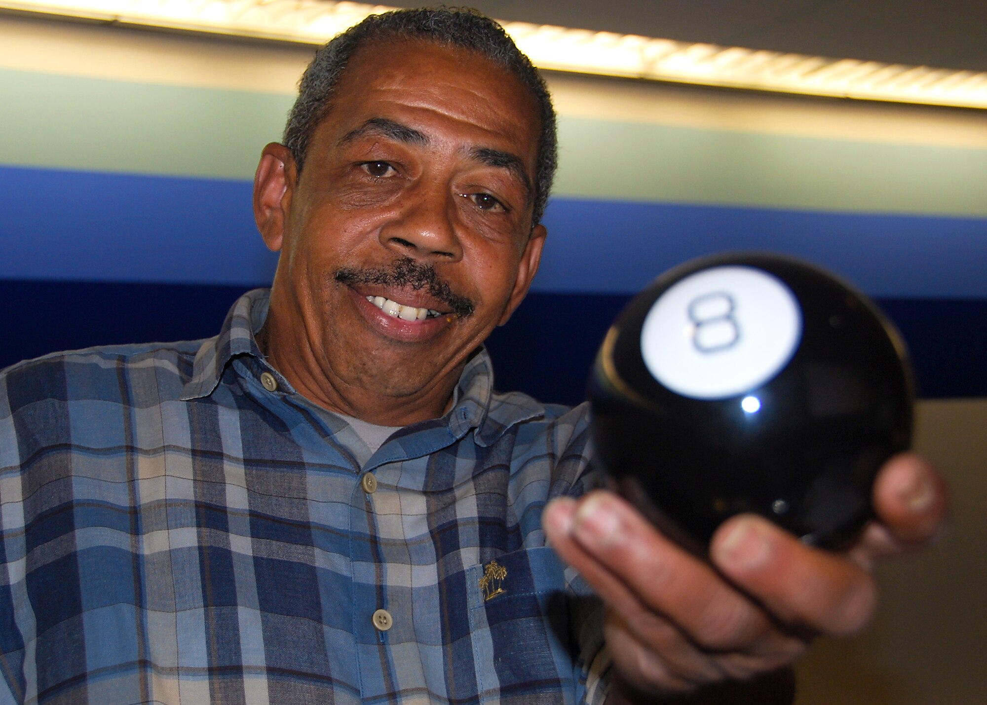 JOINT BASE MCGUIRE-DIX-LAKEHURST, N.J. -- Mark Jones, 305th Aerial Port Squadron transportation specialist, displays his Magic 8-Ball while working at the passenger terminal here Aug. 27. The fortune-telling toy contains a window, which displays predictions to yes-or-no questions after it is shaken. When travelers ask him if specific flights will launch according to schedule, Mr. Jones jokingly consults the Magic 8-Ball which offers responses such as "signs point to yes" or "outlook hazy, try again." (U.S. Air Force photo/Staff Sgt. Shawn J. Jones)