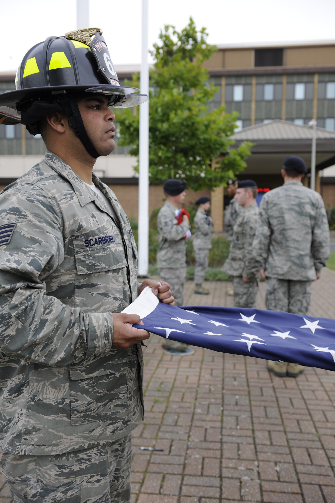 ROYAL AIR FORCE LAKENHEATH, England – Staff Sgt. Sharief Scarbriel, 48th Civil Engineer Squadron firefighter, stands at attention while holding the American flag during the 9/11 Retreat Ceremony here, Sept. 10, 2010. Sergeant Scarbriel is wearing a structural firefighting helmet in honor of firefighters who served and lost their lives. (U.S. Air Force photo/Airman 1st Class Lausanne Morgan)