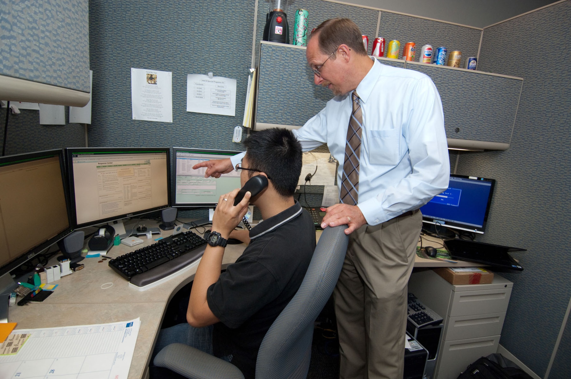 HANSCOM AIR FORCE BASE, Mass. – Ho-Ming Lee, a client system technician, and John Moseley, Response Center manager, work together to assist a customer who called 3-HELP for a computer issue on Aug. 31. In an effort to follow an Air Force-wide directive, 66th Air Base Group’s Communications and Information Division recently consolidated IT support services so customers who call the help line will receive help from a centralized team of client systems technicians. (U.S. Air Force photo by Rick Berry)