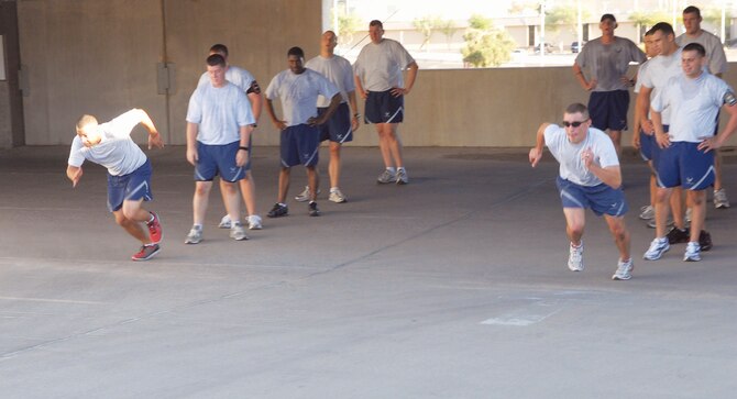 Staff Sgt. James Washington and Senior Airman R.J. Biermann race during a 'Tower of Pain' exercise on September 1st in the base exchange parking garage located on Luke Air Force Base, Ariz.  The nonstop workout consists of running, up-hill lunges, push-ups, burpees, wall sits, wall jumps, sprints and more.. (U.S. Air Force photo/Airman 1st Class Melanie Holochwost)