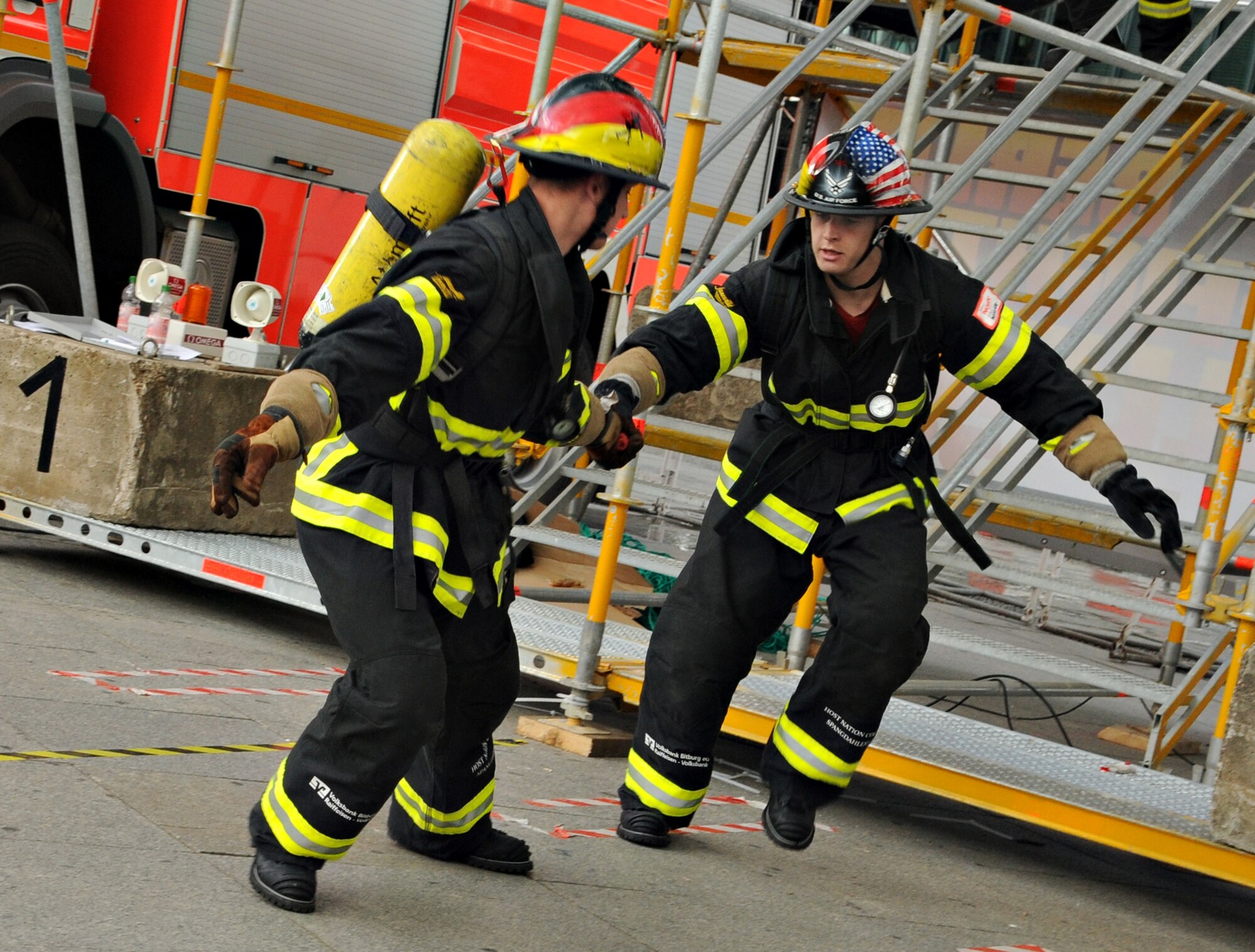 BERLIN – Senior Airman Aaron Anderson, right, hands the relay baton to Airman 1st Class Mitchel Blackwell, both 52nd Civil Engineer Squadron firefighters, during their relay race in the fourth Berlin Firefighter Combat Challenge Sept. 4. The firefighters were part of Team Spangdahlem, which placed second in the relay event with a finish time of 1 minute, 36 seconds. (U.S. Air Force photo/Staff Sgt. Benjamin Wilson)