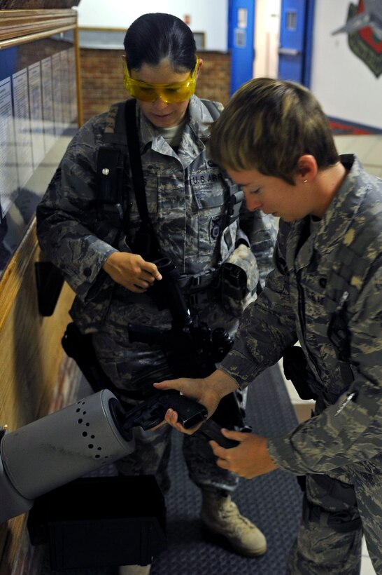 ELLSWORTH AIR FORCE BASE, S.D. - Senior Airman Elizabeth Bolanos watches as Airman 1st Class Robin Rock loads her issued M-9 pistol before their shift begins, Sept. 8.  Both Airmen are members of the 28th Security Forces Squadron Alpha Flight. (U.S. Air Force photo/Staff Sgt. Marc I. Lane)