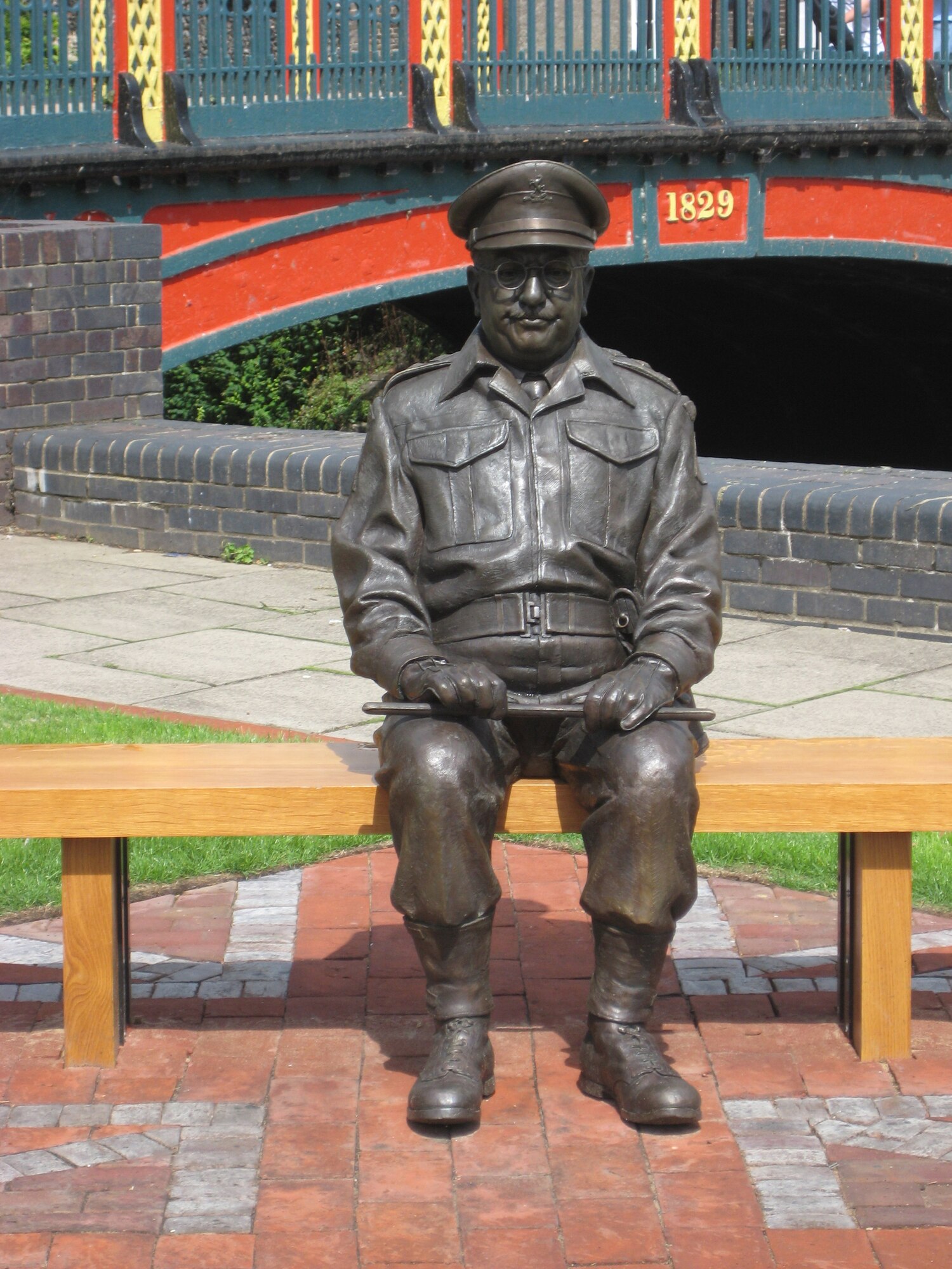 This bronze statue of Capt Mainwaring is situated close to the bridge which crosses the River Little Ouse in the centre of Thetford, Norfolk. Captain Mainwaring was the commander of the fictional World War II Home Guard unit featured in the British sitcom, "Dad's Army". Much of the series was filmed in East Anglia.The statue shows Mainwaring wearing his Home Guard uniform, seated on bench, with his baton across his knees. (U.S. Air Force photo by Suzanne Harper)