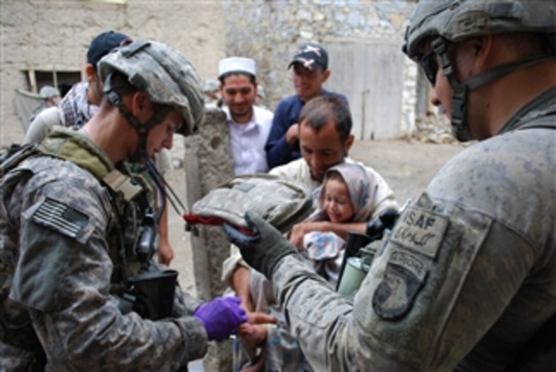 U.S. Army Sgt. Adam Morris (left), a medic with the 412th Civil Affairs Battalion, on patrol with 1st Platoon, Charlie Company, 1st Battalion, 327th Infantry Regiment, Task Force Bulldog, treats a child's wound after his father asked the passing patrol for medical assistance in Kunar province, Afghanistan, on Aug. 25, 2010.  