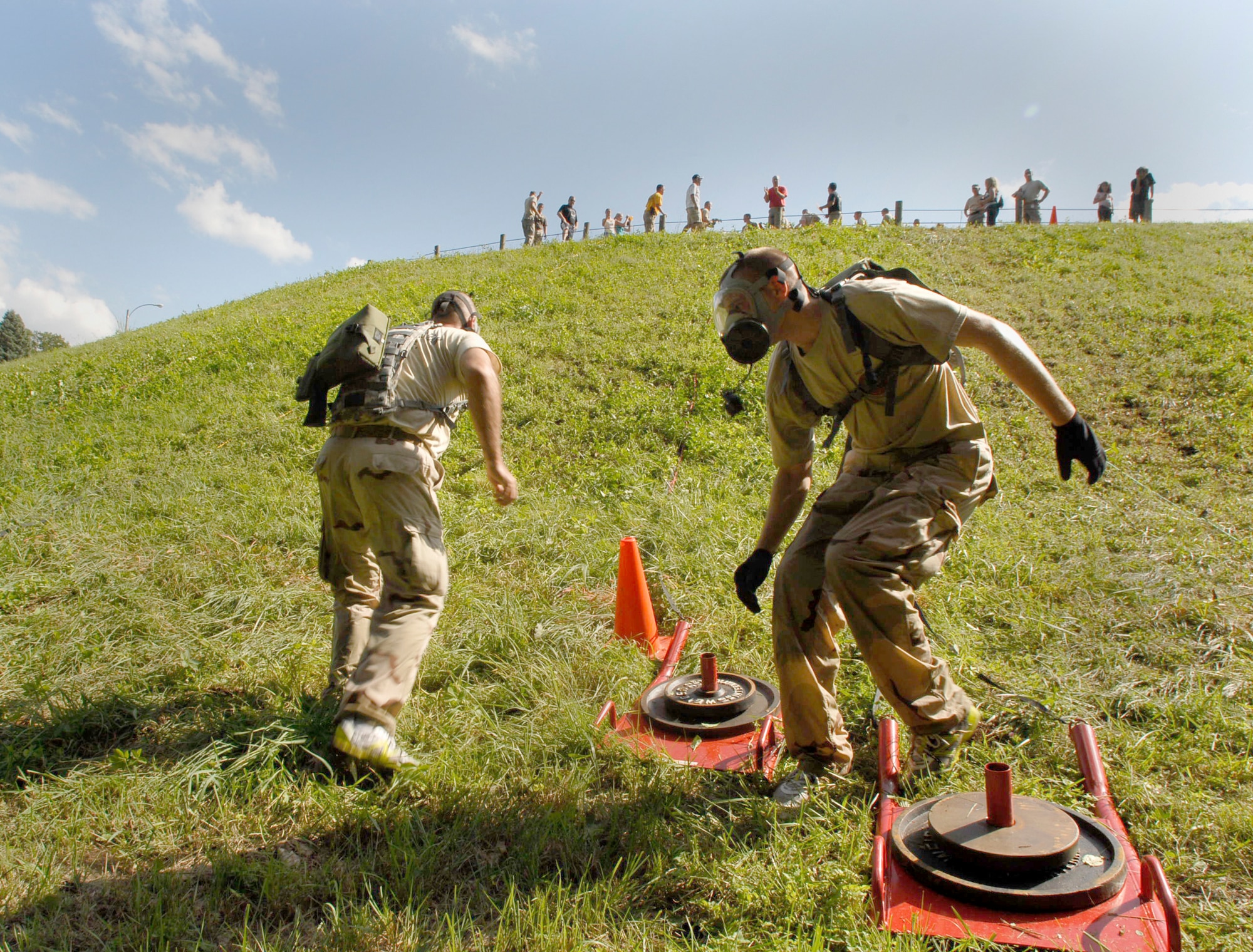 Two 103rd Security Forces Squadron personnel turn to charge back up a hill in gas masks after pulling a weighted sled during the physical fitness challenge at the Connecticut SWAT Challenge Aug. 26, 2010. The PT course this year was held at the West Hartford Reservoir and covered 4.7 miles consisting of 32 distinct obstacles. (U.S. Air Force photo by Tech. Sgt. Josh Mead)