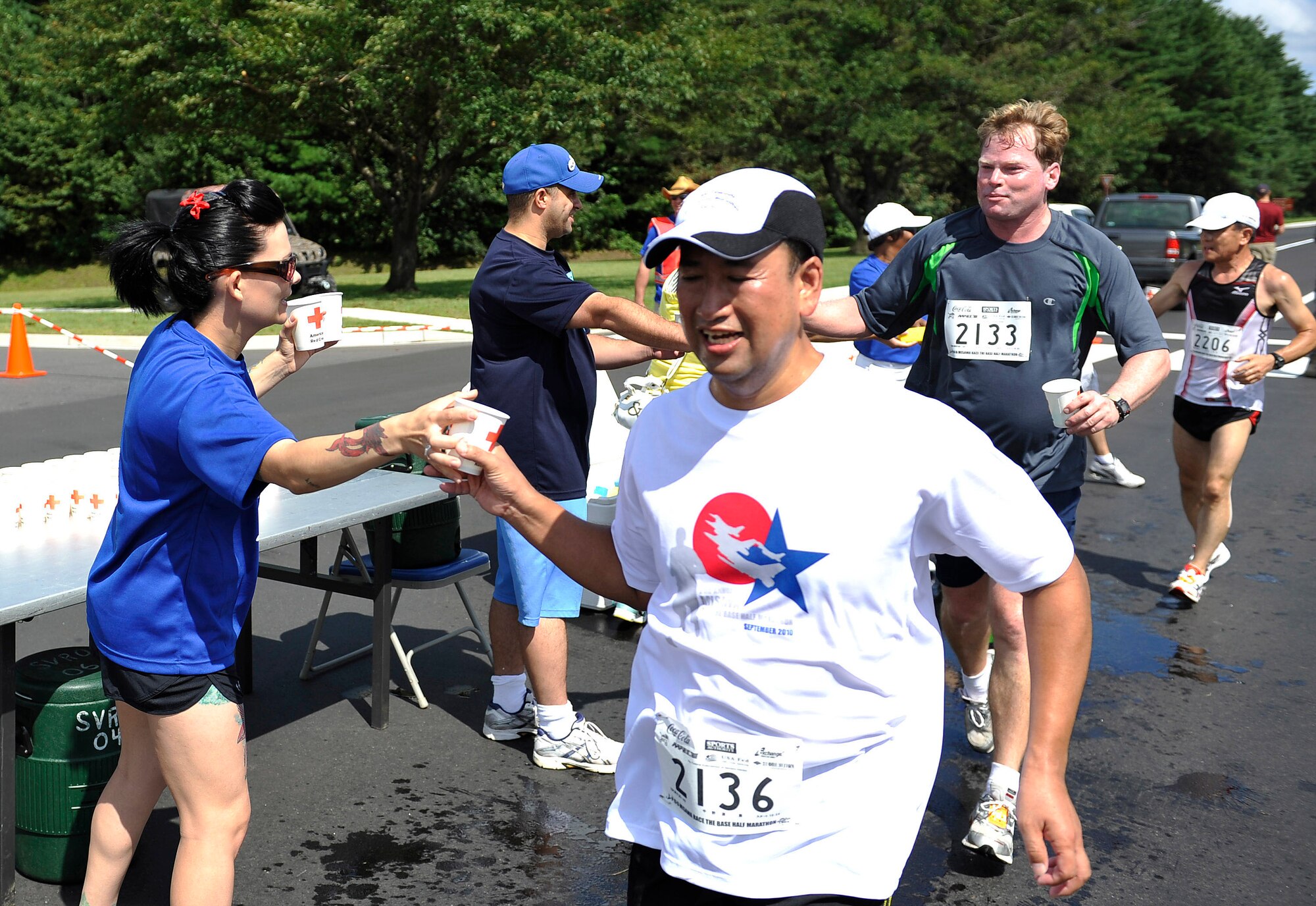 U.S. Air Force Tech. Sgt. Jamie Meadows-Valley, 35th Fighter Wing protocol specialist, hands water to Yutaka Nakanowatari during the Race the Base half-marathon Sept. 12, 2010, at Misawa Air Base, Japan. More than 180 volunteers helped during the event.  (U.S. Air Force photo/Staff Sgt. Chad C. Strohmeyer/Released)