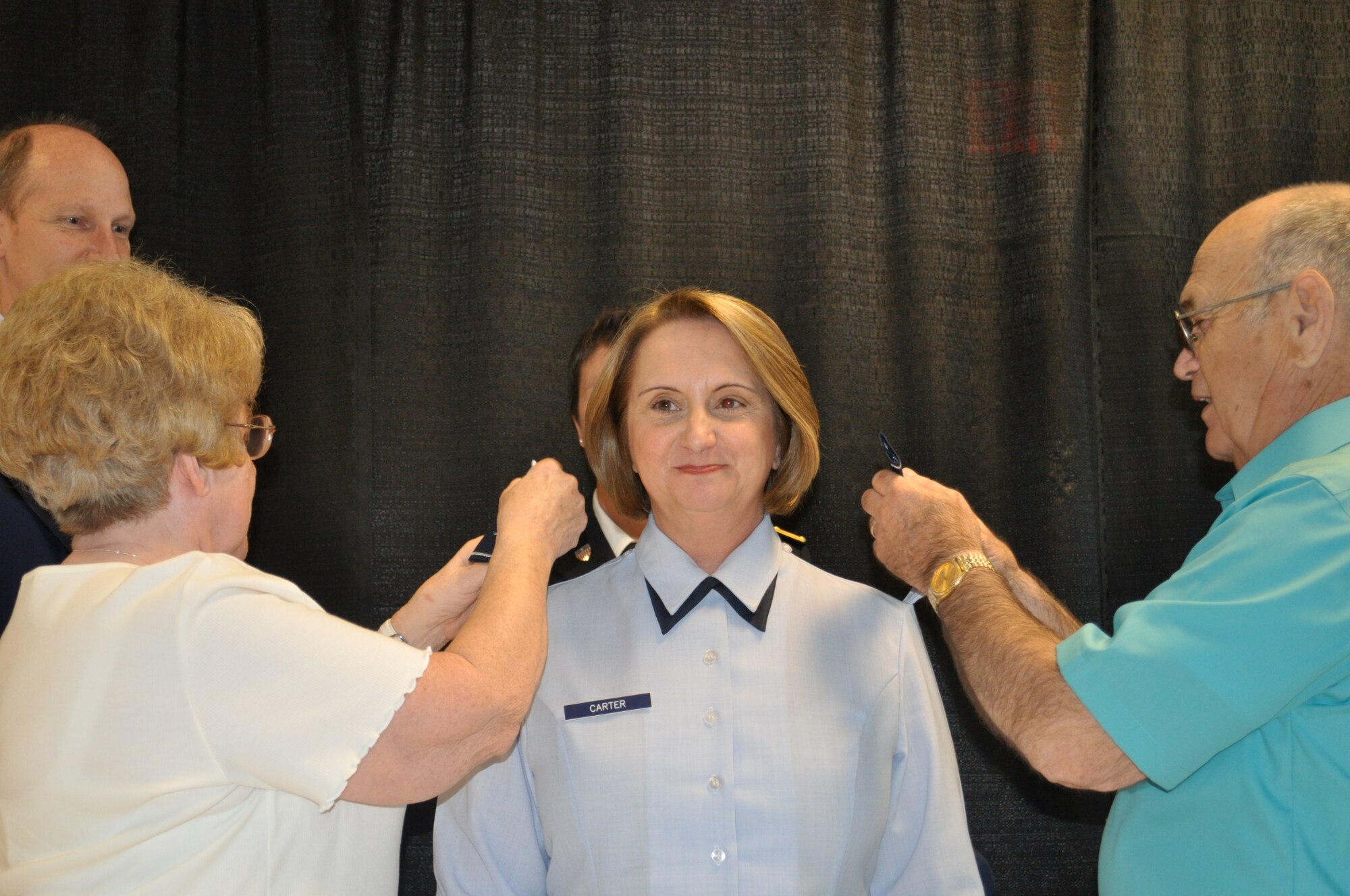 Carter's father Gene Gelinas, and his wife Helen replace colonel epaulets with brigadier general epaulets during her promotion ceremony May 28.