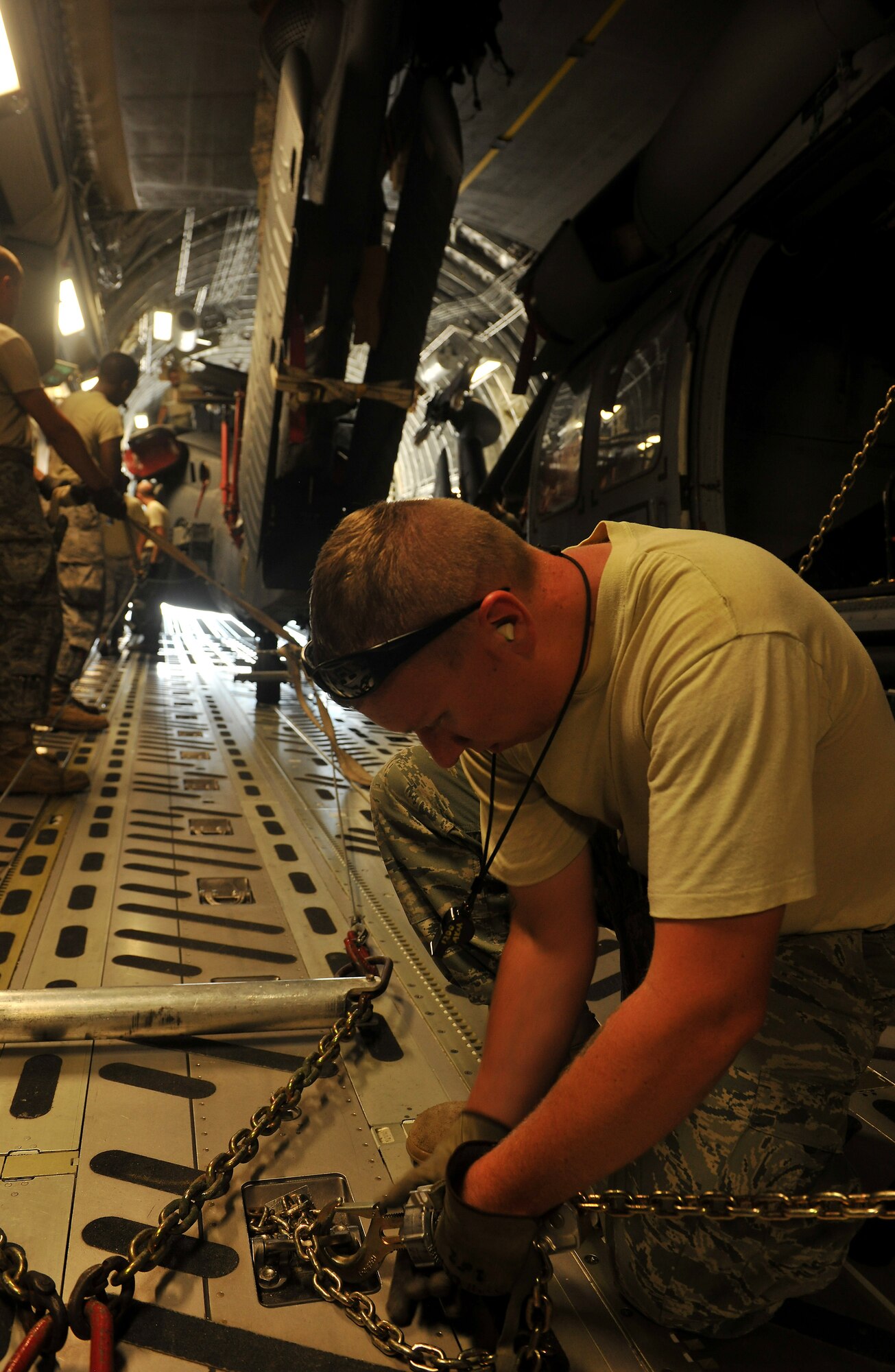 MOODY AIR FORCE BASE, Ga. -- Staff Sgt. Justin Klier, 41st Rescue Squadron crew chief, locks chains in place after a group of Airmen load an HH-60G Pave Hawk onto the back of a C-17 Globemaster III here Sept. 3. The aircraft will be transported to Afghanistan in support of a deployment. (U.S. Air Force photo/Airman 1st Class Joshua Green)

