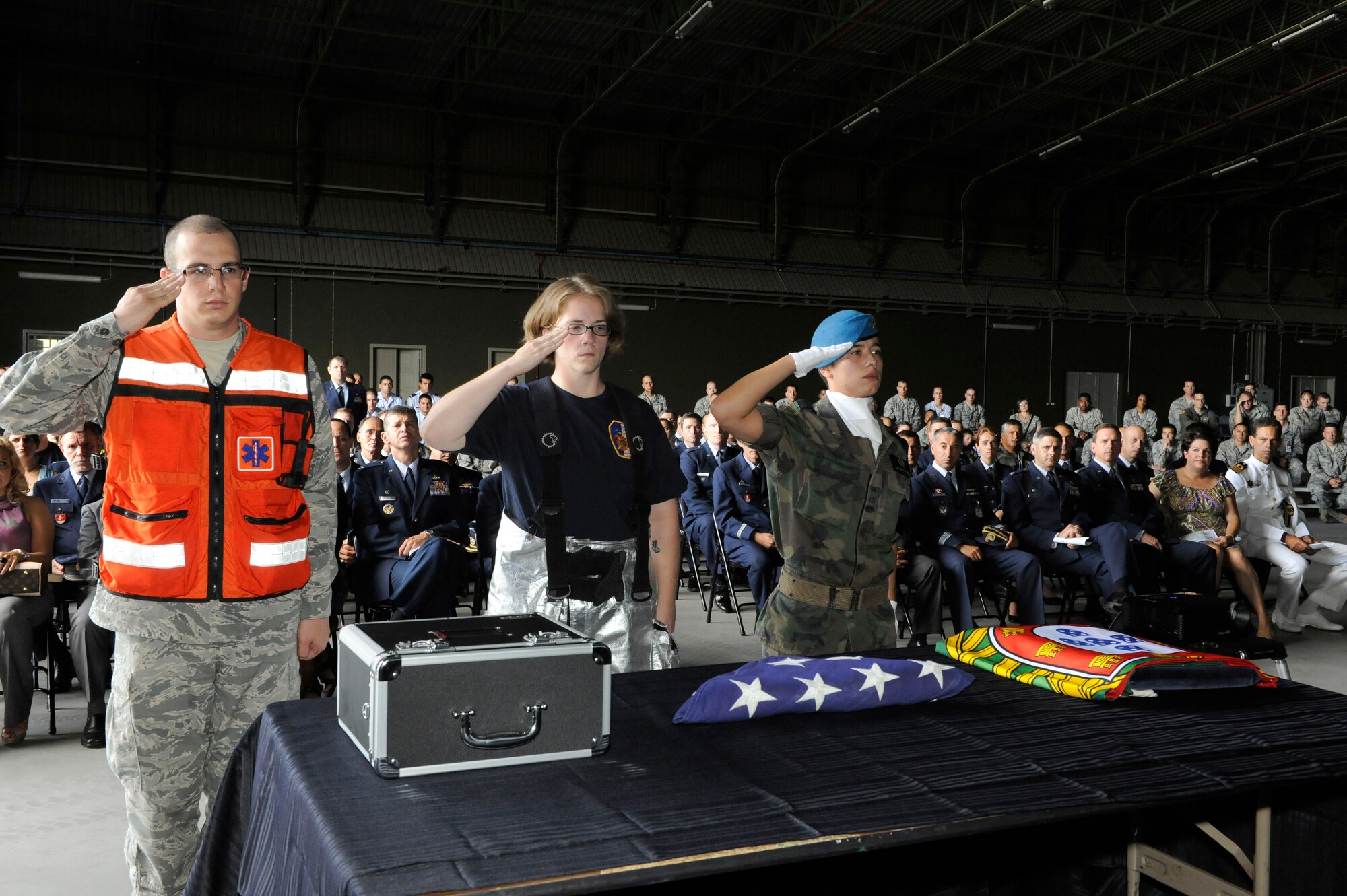 (From left) Airman 1st Class Stephen Brasher, 65th Medical Group, Senior Airman Cori Rinehart, 65th Civil Engineer Squadron, and Simone Costa, Portuguese Air Force Airman, salute the flags during the Sept. 11 ceremony held in the Portuguese Hanger, 65th Air Base Wing, Lajes Field, Sept. 10, 2010.  (U.S. Air Force photo by Guido Melo)