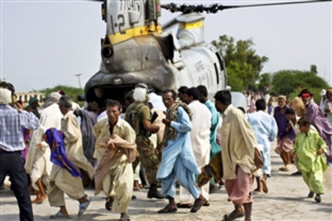 Pakistani flood victims gather as U.S Marines and Pakistani soldiers begin to unload relief supplies from a CH-46E Sea Knight helicopter during humanitarian assistance efforts in southern Pakistan, Sept. 11, 2010. The Marines are assigned to Marine Medium Helicopter Squadron 165, 15th Marine Expeditionary Unit.