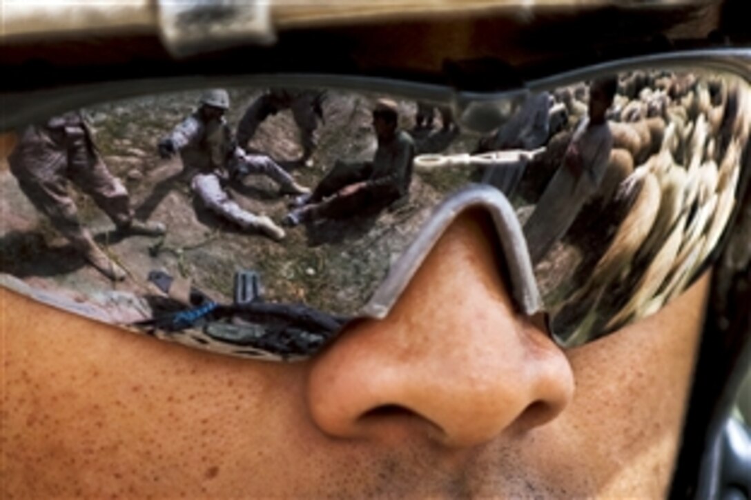 U.S. Marine Corps Cpl. Anthony Patris reflects a scene in his sunglasses as his interpreter speaks with Afghan boys after an improvised explosive device detonated in Pinjadoo in Afghanistan's Helmand province, Sept. 6, 2010. The explosion did not injure any Marines or Afghans. Patris is a vehicle commander assigned to Headquarters Company, 3rd Battalion, 3rd Marine Regiment.