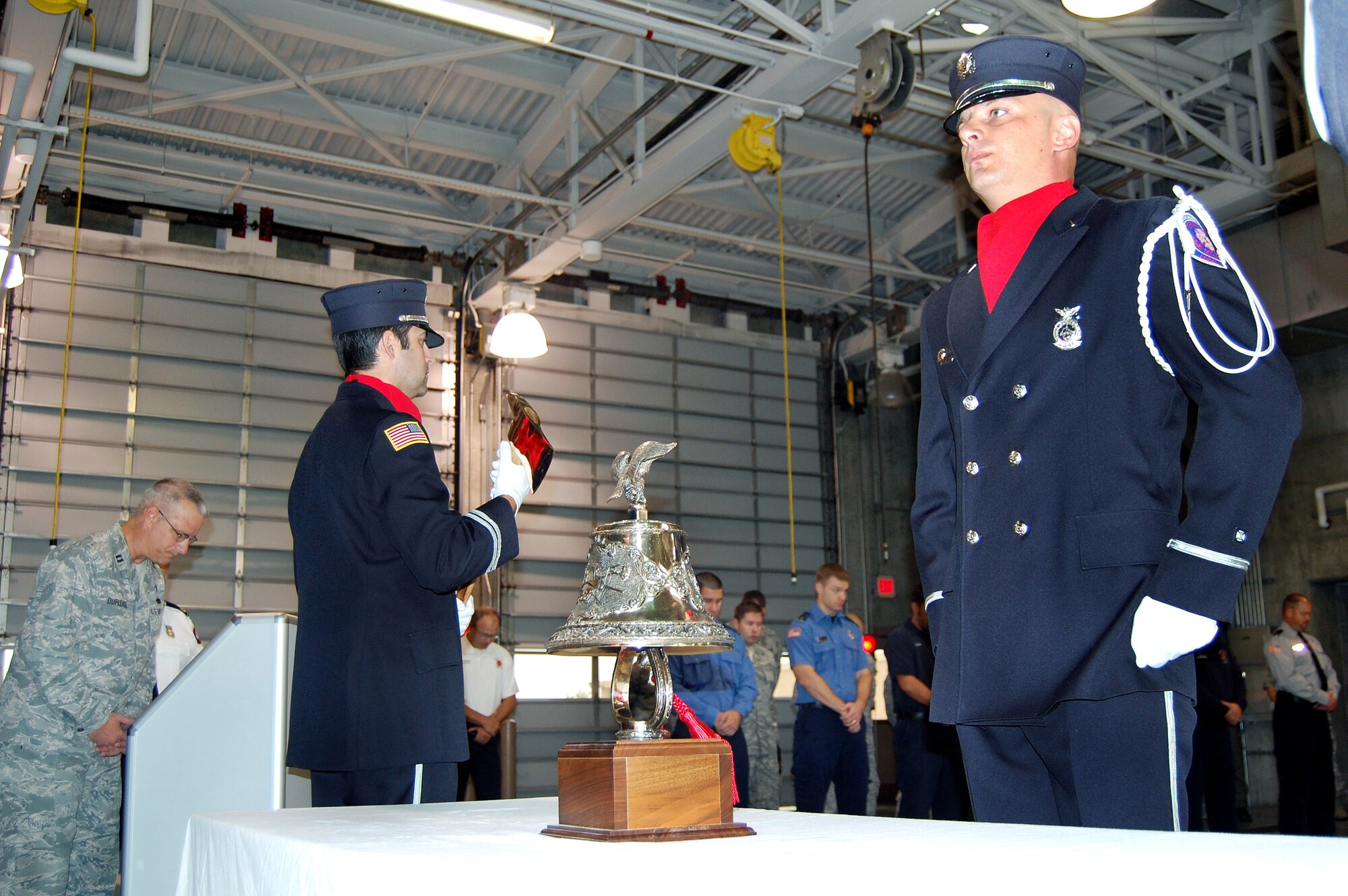 OFFUTT AIR FORCE BASE, Neb. - (From left) Chaplain (Capt.) Robert Duplease gives the innvocation during the Offutt Fire Department's 9/11 Remembrance Ceremony Sept. 10 in the bay of the fire station while ceremonial guard members Fire Captain Jason Bloom and Firefighter Brent Bergstrom stand at attention.  The annual ceremony, held during morning roll call, included the final alarm given to honor firefighters who have lost their lives in the line of duty. According to Station Chief Roger Filter, the tradition of the final alarm, consiting of two sets of five bell rings, dates back to the days of horse and buggy firefighters when alarm boxes were located around cities so people could notify fire departments of fires. They were also used  to notify citizens of the death of a firefighter.  U.S. Air Force photo by Debbie Aragon