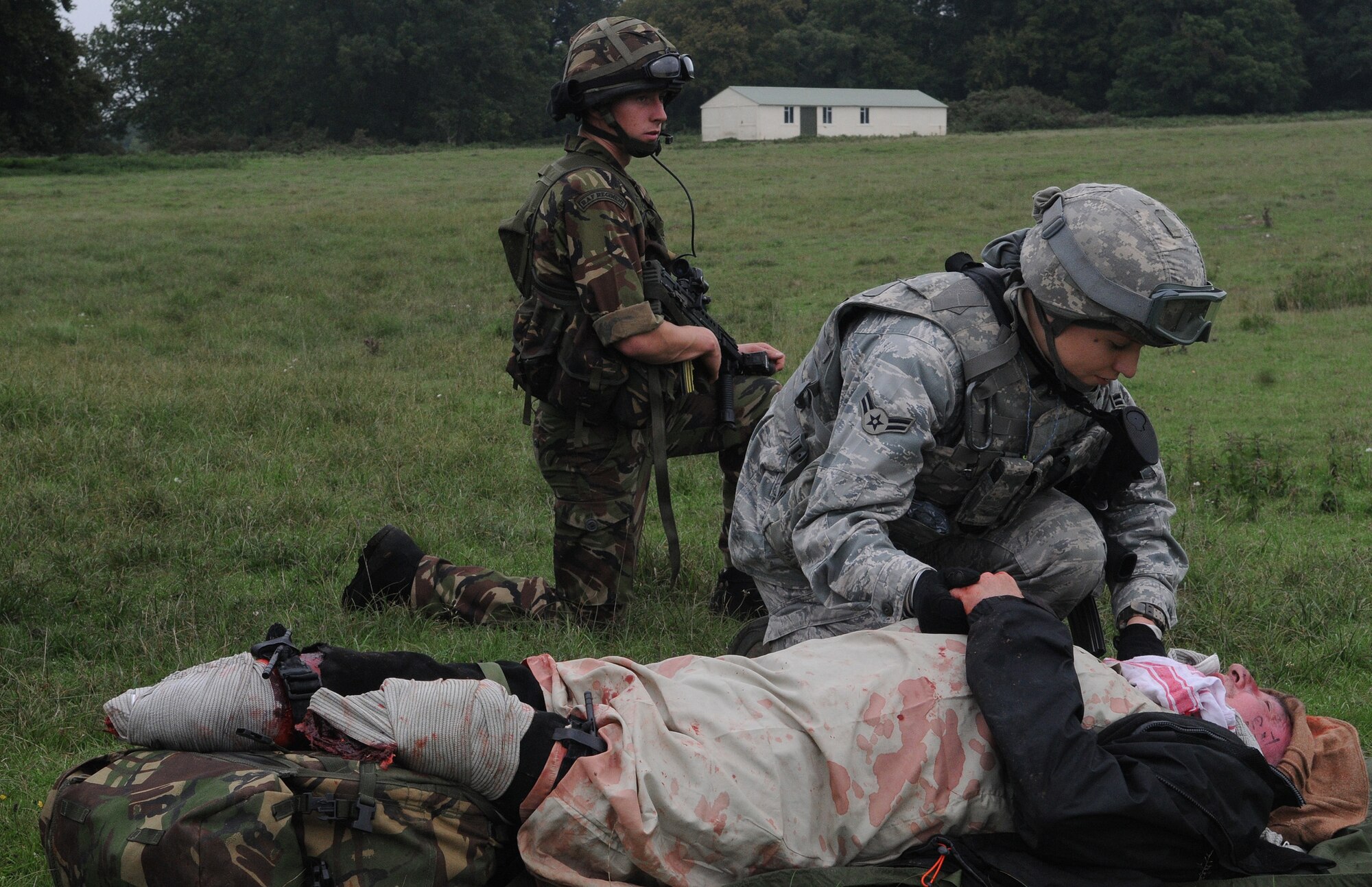 STANFORD TRAINING AREA, England -- Airman 1st Class Ali Rickman, 100th Security Forces Squadron (right), comforts a "patient" while a member of the Royal Air Force Regiment provides security as they await helicopter transport during a mass casualty training scenario here Sept. 8. More than 20 Airmen embedded in training with the regiment to give the British servicemembers an idea of what it is like to work with United States forces. In this scenario, Afghan contractors, each with some type of amputation, portrayed victims of an improvised explosive device attack and servicemembers provides first aid. The regiment flight was conducting its last training scenarios before deploying to Afghanistan with U.S. Marines. (U.S. Air Force photo/Staff Sgt. Thomas Trower) 