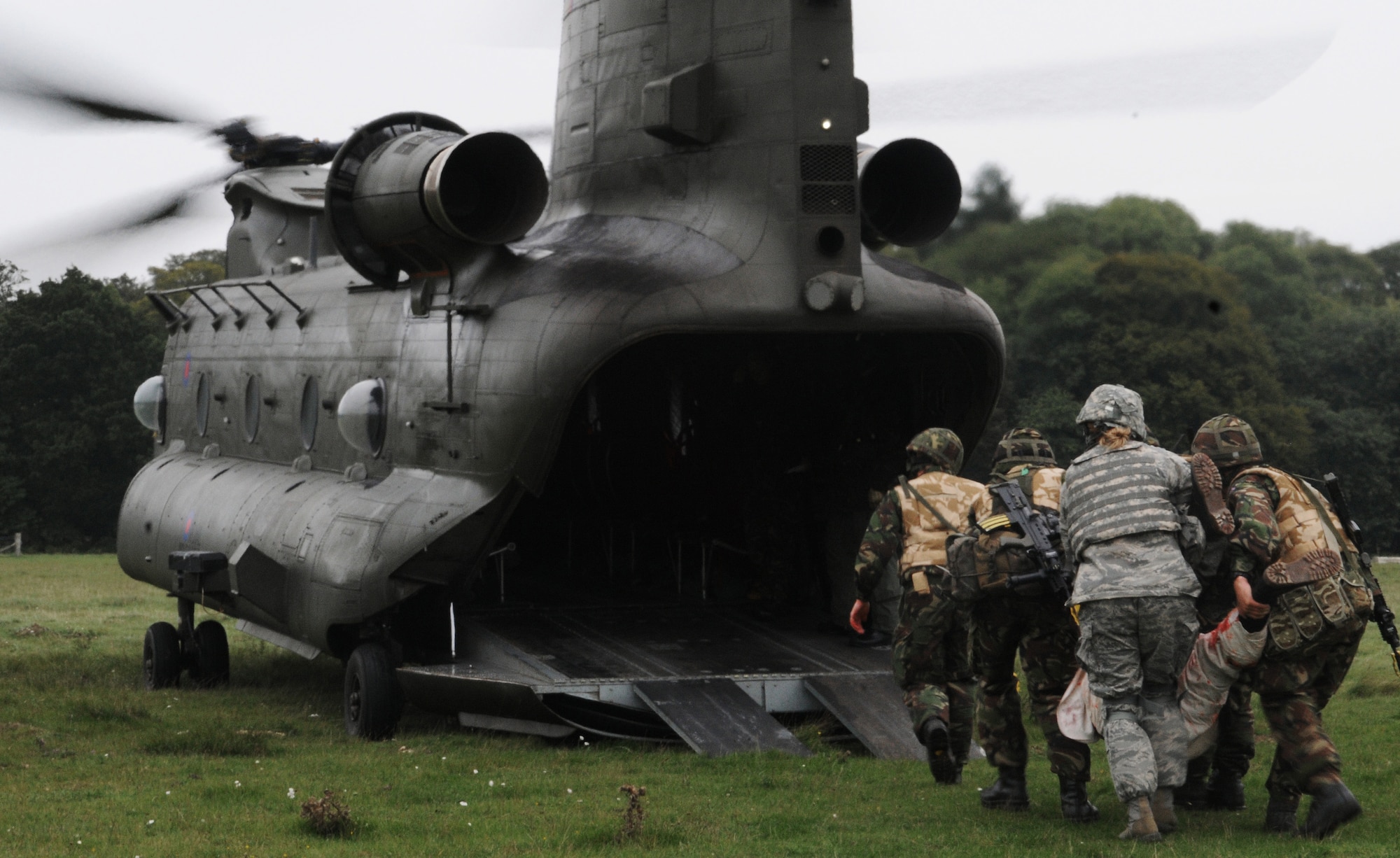 STANFORD TRAINING AREA, England -- Members of the Royal Air Force Regiment and Tech. Sgt. Tisha Bate, 100th Security Forces Squadron, carry a "patient" into an RAF Chinook as part of a mass casualty training scenario here Sept. 8. The regiment flight was conducting its last training scenarios before deploying to Afghanistan. U.S. Airmen embedded into the training to fill the place of U.S. Marines that the British force would be working side by side with on their deployment. (U.S. Air Force photo/Staff Sgt. Thomas Trower) 