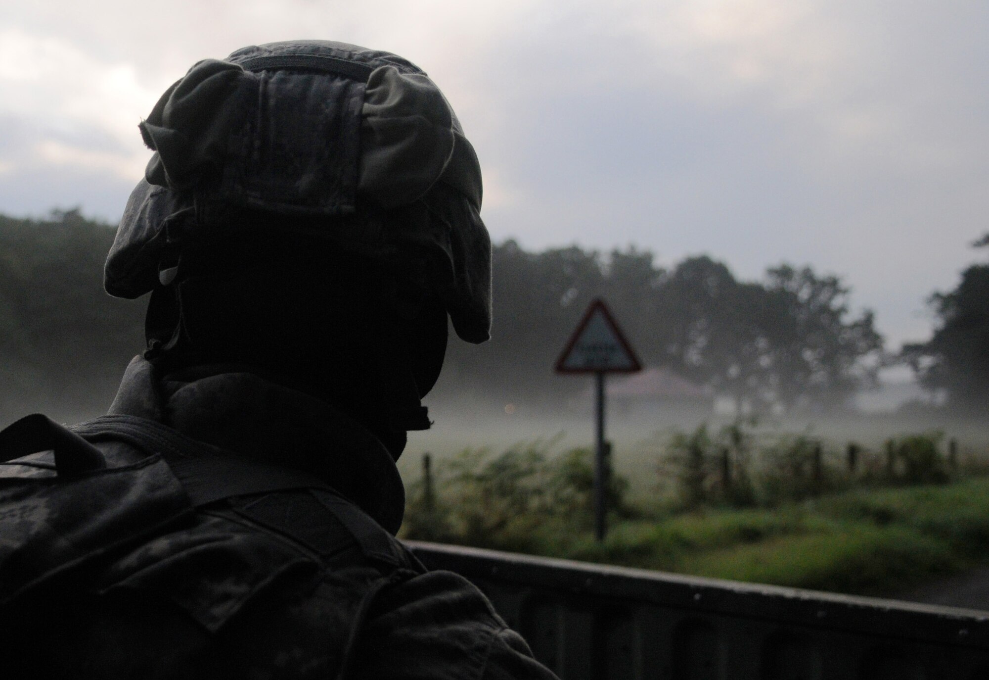 STANFORD TRAINING AREA, England -- A 100th Security Forces Squadron Airman looks out over a fog-covered field  while convoying with Royal Air Force Regiment servicemembers to conduct a key leadership engagement training mission in a nearby mock Afghan village Sept. 9. The British forces were conducting their last training scenarios before deploying to Afghanistan. More than 20 U.S. Airmen embedded into the training to fill the place of U.S. Marines that the British force would be working side by side with on their deployment. (U.S. Air Force photo/Staff Sgt. Thomas Trower) 
