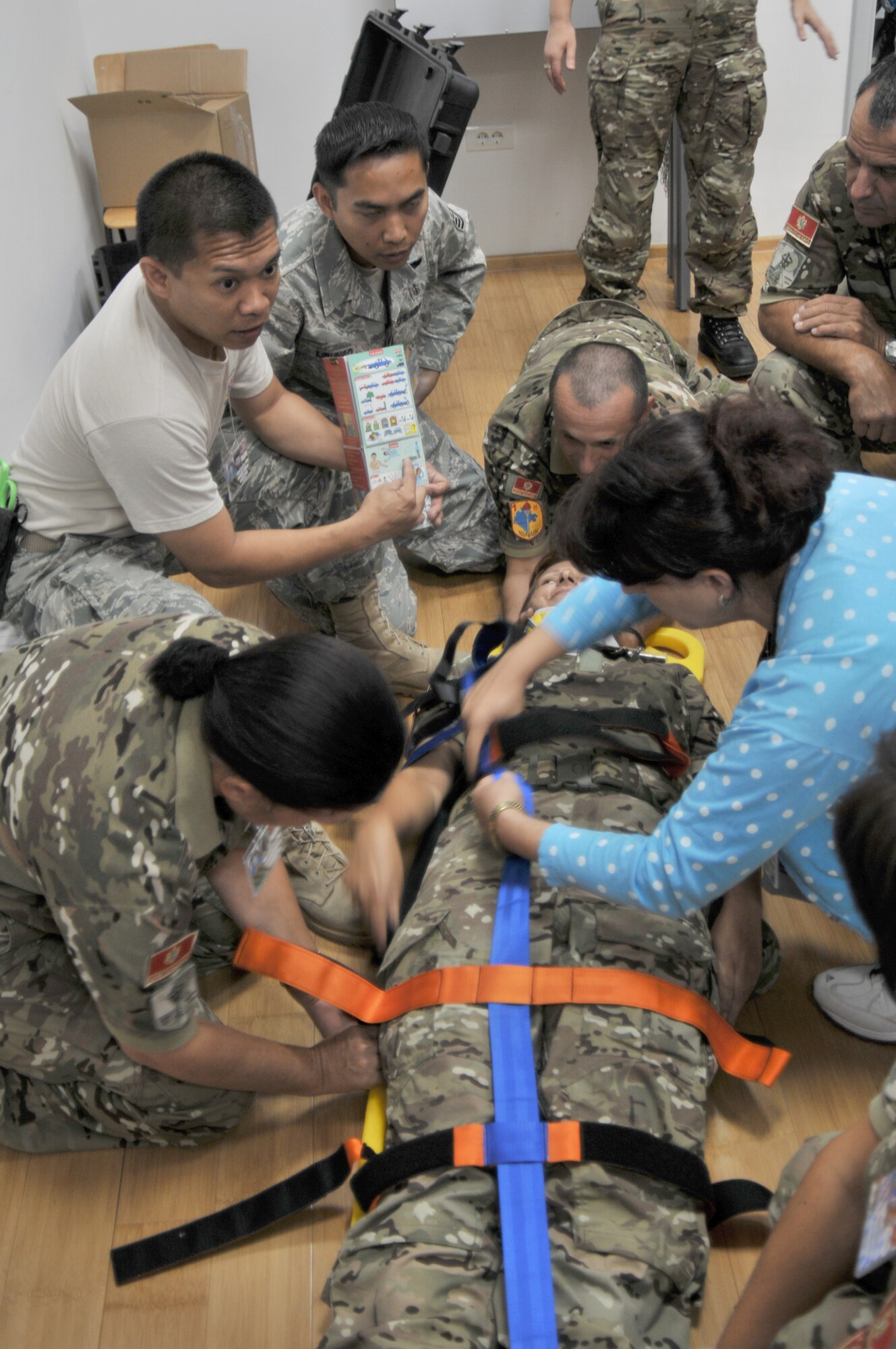Staff Sgt. Vince Remo (in t-shirt) and Tech. Sgt. Jose Libunao work with members of the Montenegrin army Sept. 14, 2010 through the procedures of securing a patient to a stretcher during a class at Medical Training Exercise in Central & Eastern Europe 2010 held at Danilovgrad Army Base, Montenegro. Sergeant Remo is using a medical translation pamphlet that features symbols instead of words to quickly overcome the language barrier. MEDCEUR10 is a medical training exercise including servicemembers from 10 nations. (U.S. Air Force photo/Senior Airman David Dobrydney)
