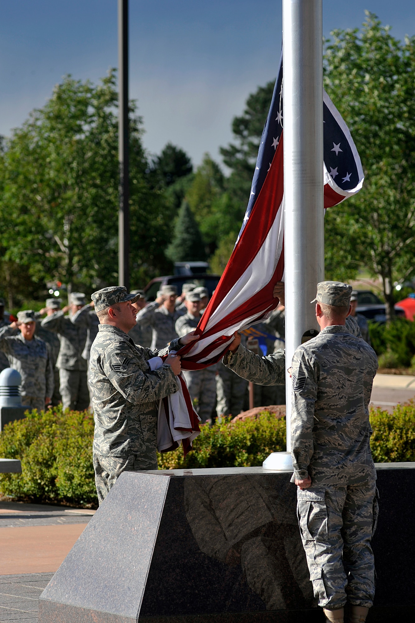 Members of the 21st Medical Group lower the flag during a retreat ceremony hosted by the group Aug. 31, at the 21st Space Wing headquarters building on Peterson Air Force Base. A retreat ceremony is held the last duty day of the month at Building 845, hosted by one of the 21st Space Wing’s groups. The retreat ceremony serves a twofold purpose. It signals the end of the official duty day and serves as a ceremony for paying respect to the flag. (U.S. Air Force photo/ Larry Hulst)