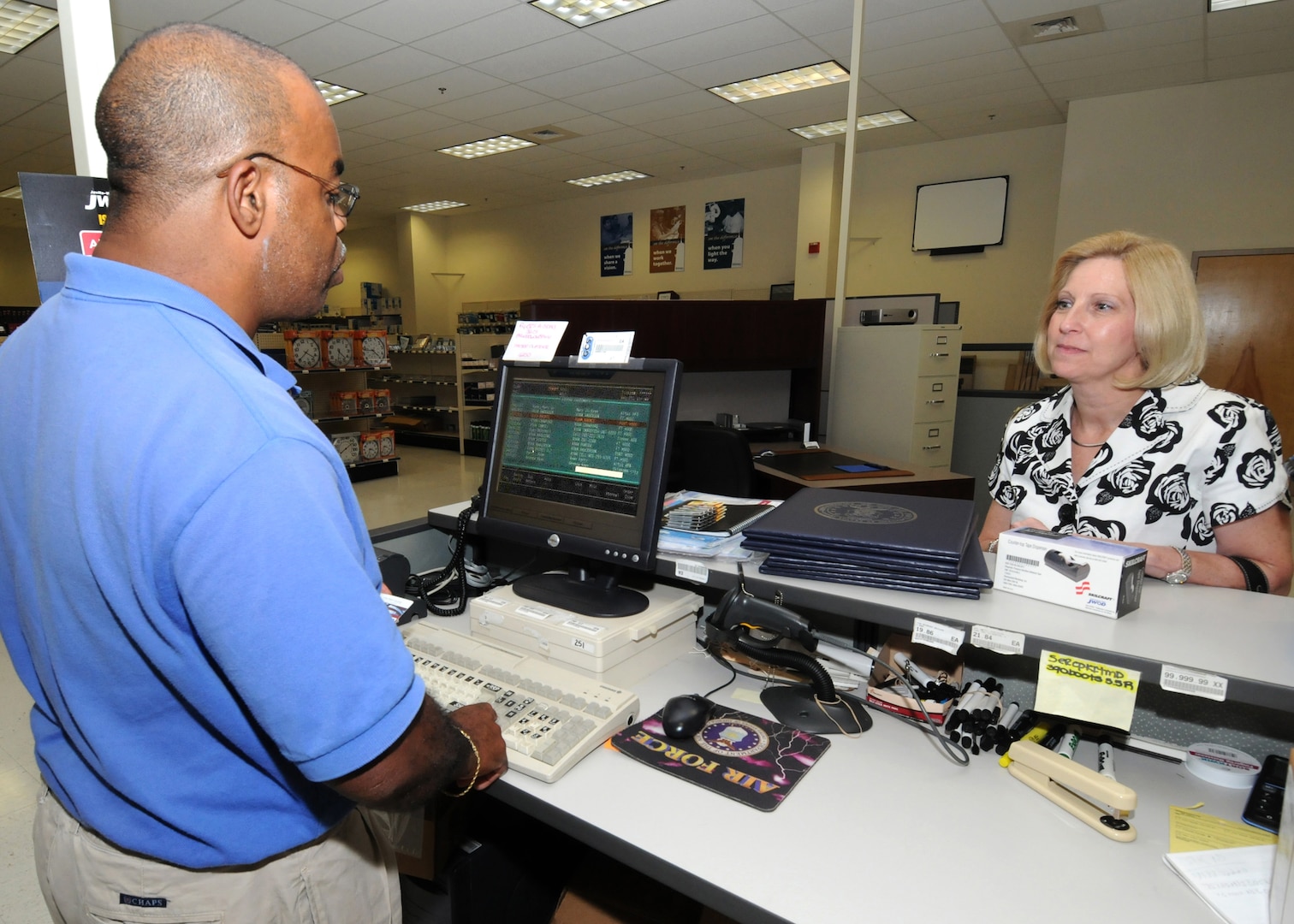 Willie Wilson, a cashier at the Randolph Base Service Center, assists customer Fran Ryan, a workflow manager with A4/7.  Mr. Wilson has problems reading small text, so a computer program for the visually impaired enlarges text on his computer screen.(U.S. Air Force photo/David Terry)