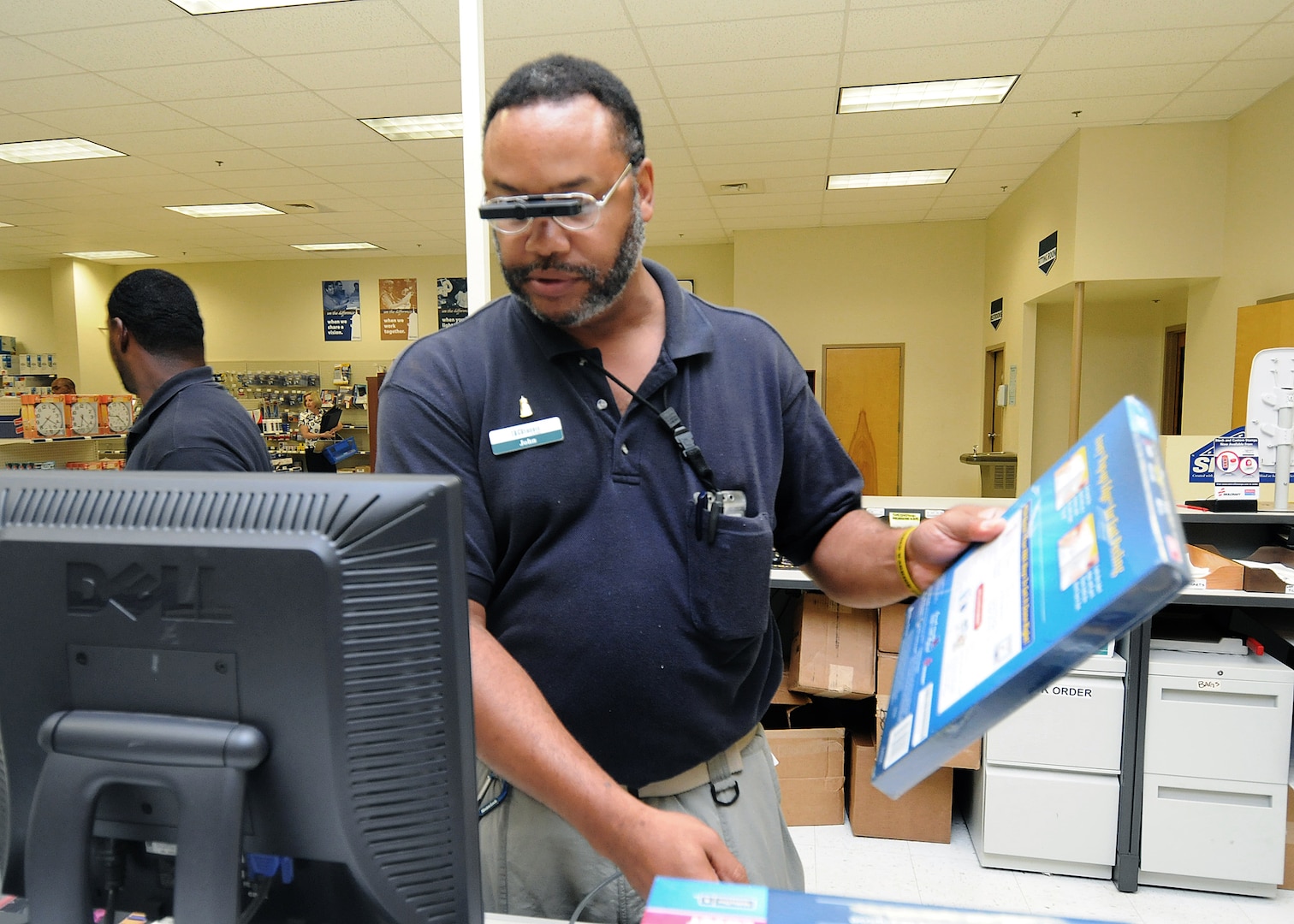 A monocular attached to his glasses allows cashier John Woolridge to read small text at the Randolph Base Service Center. The optical device and a special program which enlarges text on the computer screen has enabled Mr. Woolridge to perform his duties. (U.S. Air Force photo/David Terry)
