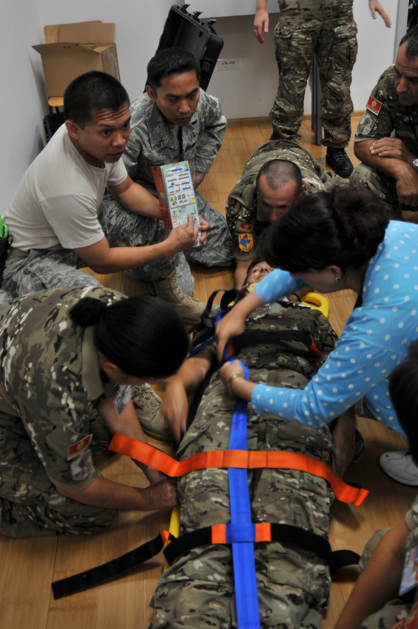 U.S. Air Force Staff Sgt. Vince Remo (in t-shirt) and Tech. Sgt. Jose Libunao and members of the Montenegrin Army work through the procedures of securing a patient to a stretcher during a class at MEDCEUR10 Sept. 14 at Danilovgrad Army Base, Montenegro. Sergeant Remo is using a medical translation pamphlet that features symbols instead of words to quickly overcome the language barrier. MEDCEUR10 is a medical training exercise including servicemembers from 10 nations. For more information, go to www.usafe.af.mil/medceur.asp and www.odbrana.gov.me. (U.S. Air Force photo/Senior Airman David Dobrydney)
