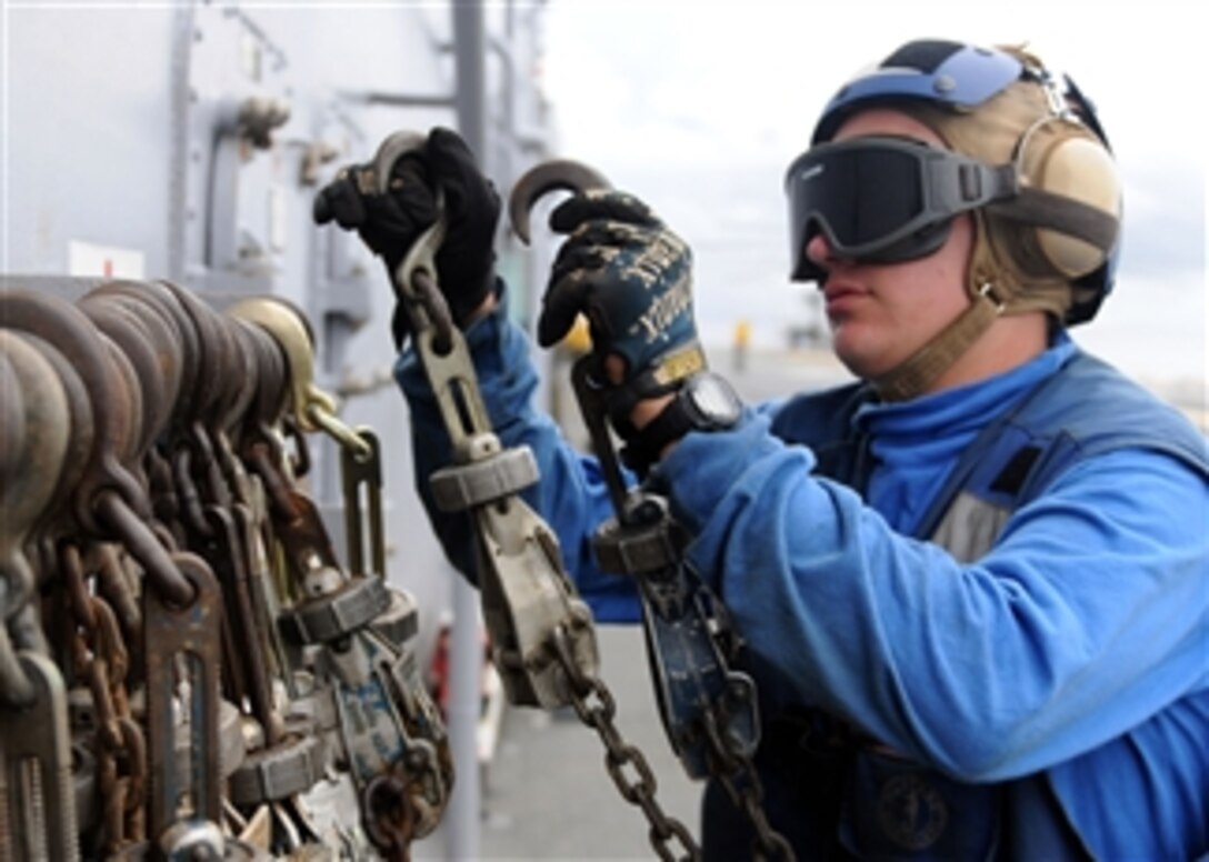 U.S. Navy Airman Recruit Jeremy J. New stows tie-down chains after removing them from a CH-46E Sea Knight helicopter aboard the USS Essex (LHD 2) in the Philippine Sea on Sept. 13, 2010.  
