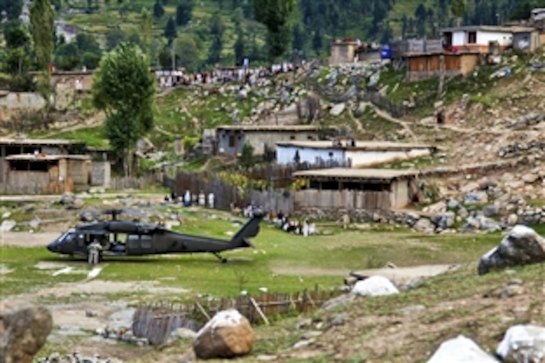Pakistanis watch from the distance as U.S. and Pakistani troops unload supplies from a CH-60 Black Hawk  helicopter in Khyber-Pakhtunkhwa, Pakistan, Sept. 13, 2010. The flood has affected nearly 20 million Pakistanis, forcing many from their homes. 