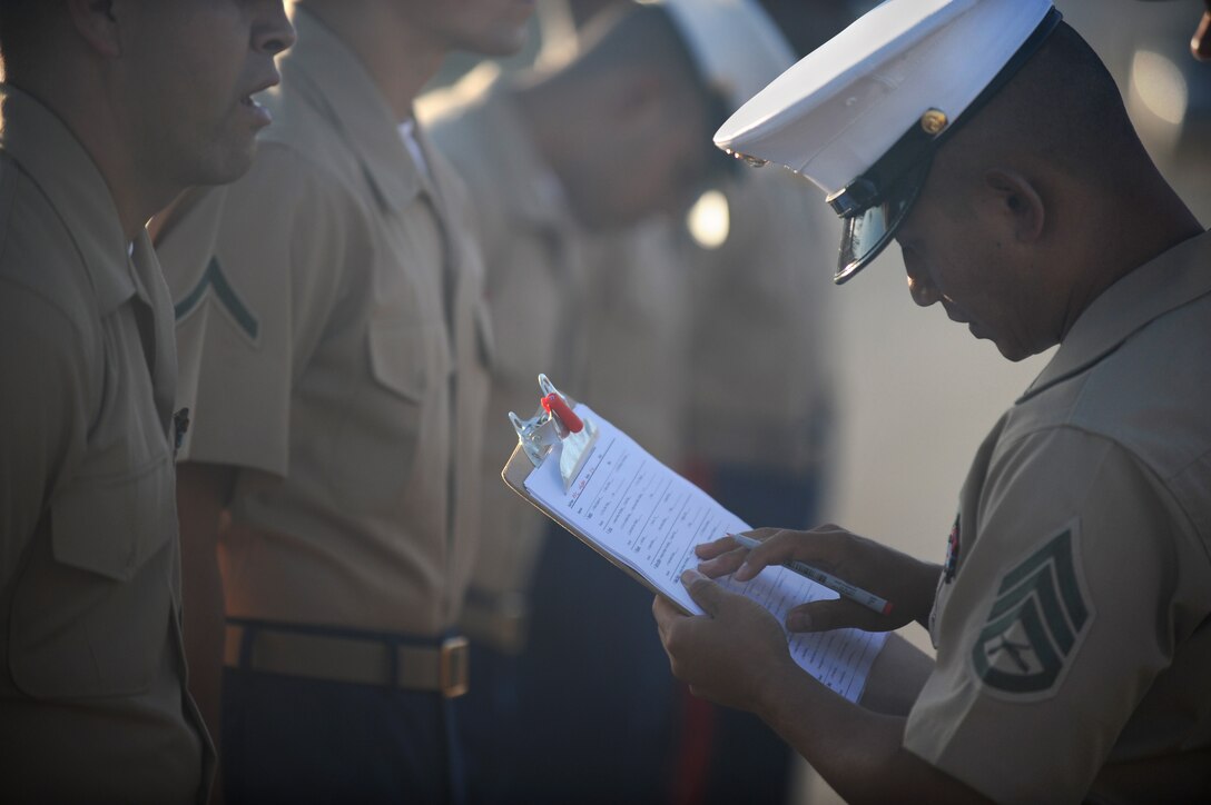 Staff Sgt. Memora Tan, 27, radio chief for the 11th Marine Expeditionary Unit, tabulates Pfc. Cody Hudzik's score during the unit's dress blue "D" uniform inspection here Sept. 14. The inspection was the unit's second official examination of uniforms in the last four weeks as the Marines prepare for San Francisco Fleet Week, Oct. 7-12. Tan is from Orange County, Calif.
