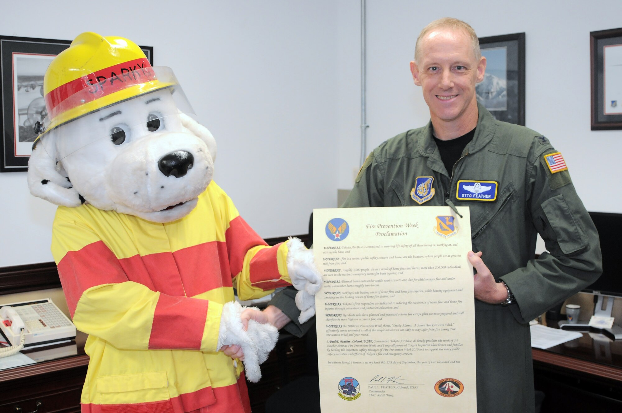 YOKOTA AIR BASE, Japan -- Col. Otto Feather, 374th Airlift Wing commander, and Sparky the Fire Dog hold the proclamation letter declaring October 3-9 as fire prevention week, here September 15. During fire prevention week the Yokota Fire Department will sponsor activities for children across the base to educate Yokota residents on fire prevention and detection. This year's theme is "Smoke Alarms: A Sound You Can Live With." (U.S. Air Force photo/Airman 1st Class Katrina R. Menchaca)