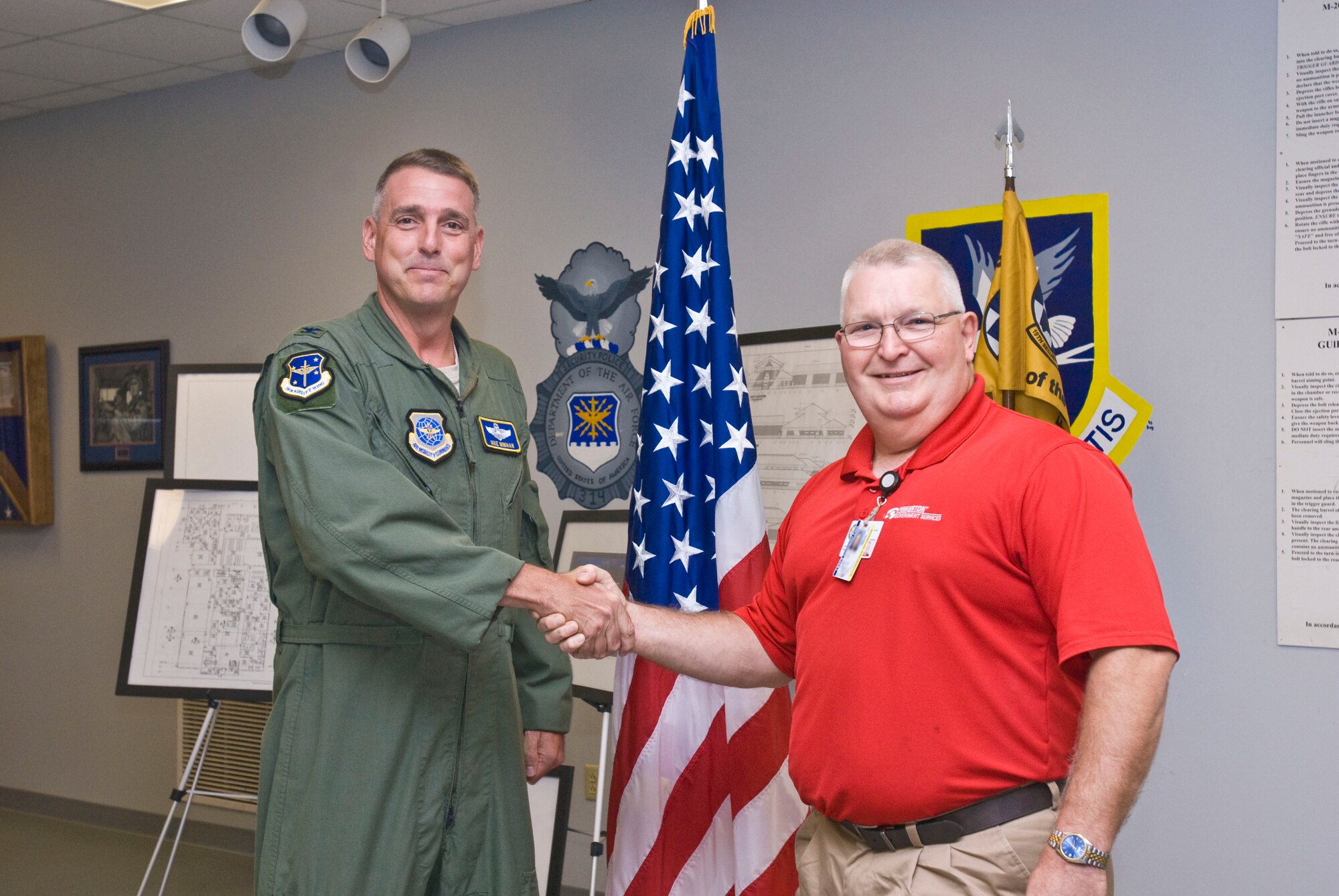 Col. Mike Minihan (left), 19th Airlift Wing commander, presented a coin Tuesday to Roland Black, 19th Security Forces Squadron Pinkerton site manager, for his selection as the Combat Airlifter of the Week. Mr. Black processed more than 158,000 vehicles and pedestrians that entered the base between July 15 and Aug. 15. (U.S. Air Force photo by Staff Sgt. Nestor Cruz)